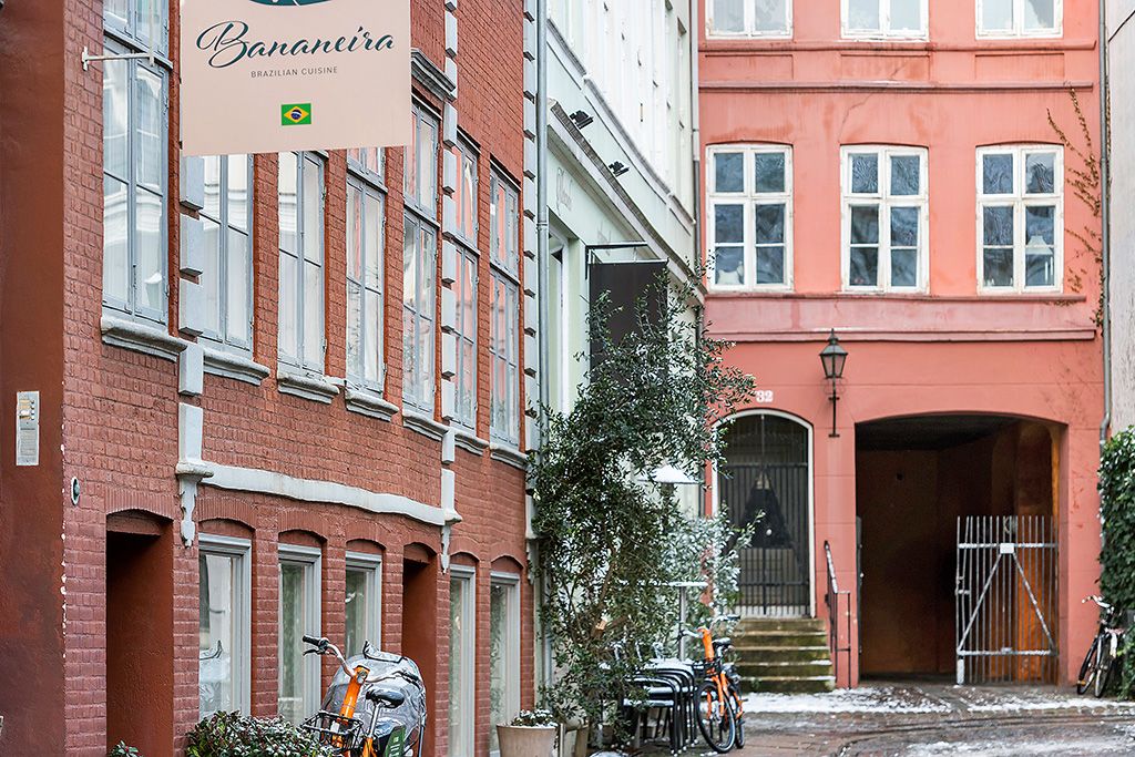 Bygning med banner "Bananeirå" i rødt murværk med flere vinduer og enkelte cykler parkeret udenfor