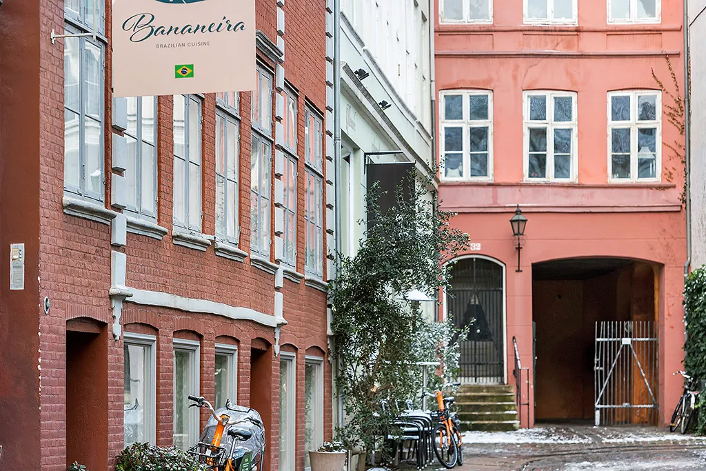 Bygning med banner "Bananeirå" i rødt murværk med flere vinduer og enkelte cykler parkeret udenfor