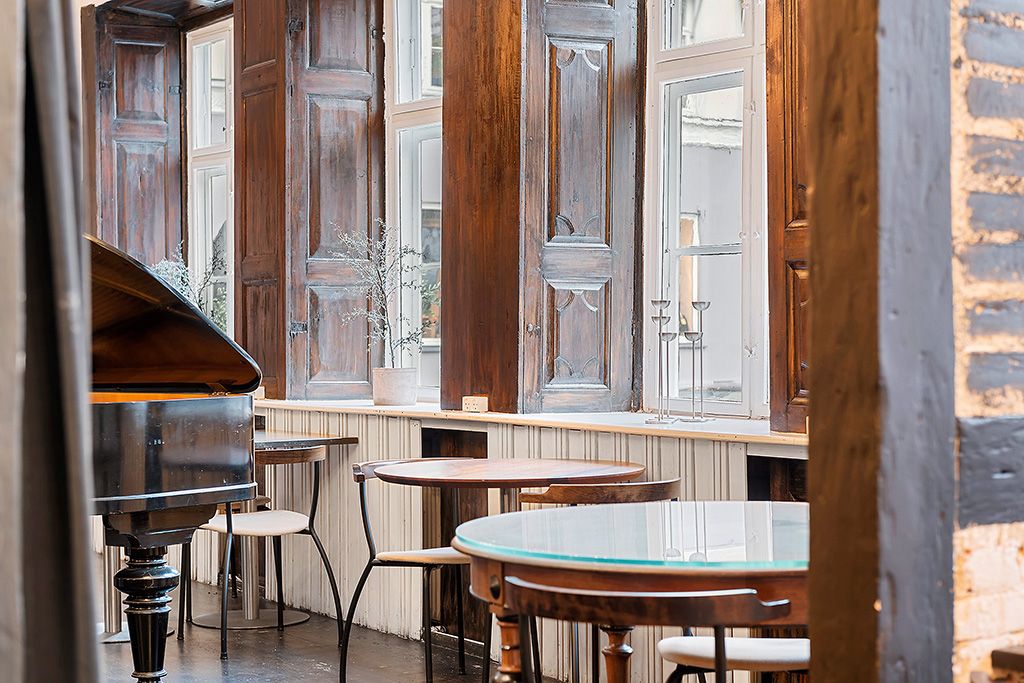 En træklaver i et skovhylde interiør med runde borde og stole samt et vinduesparti