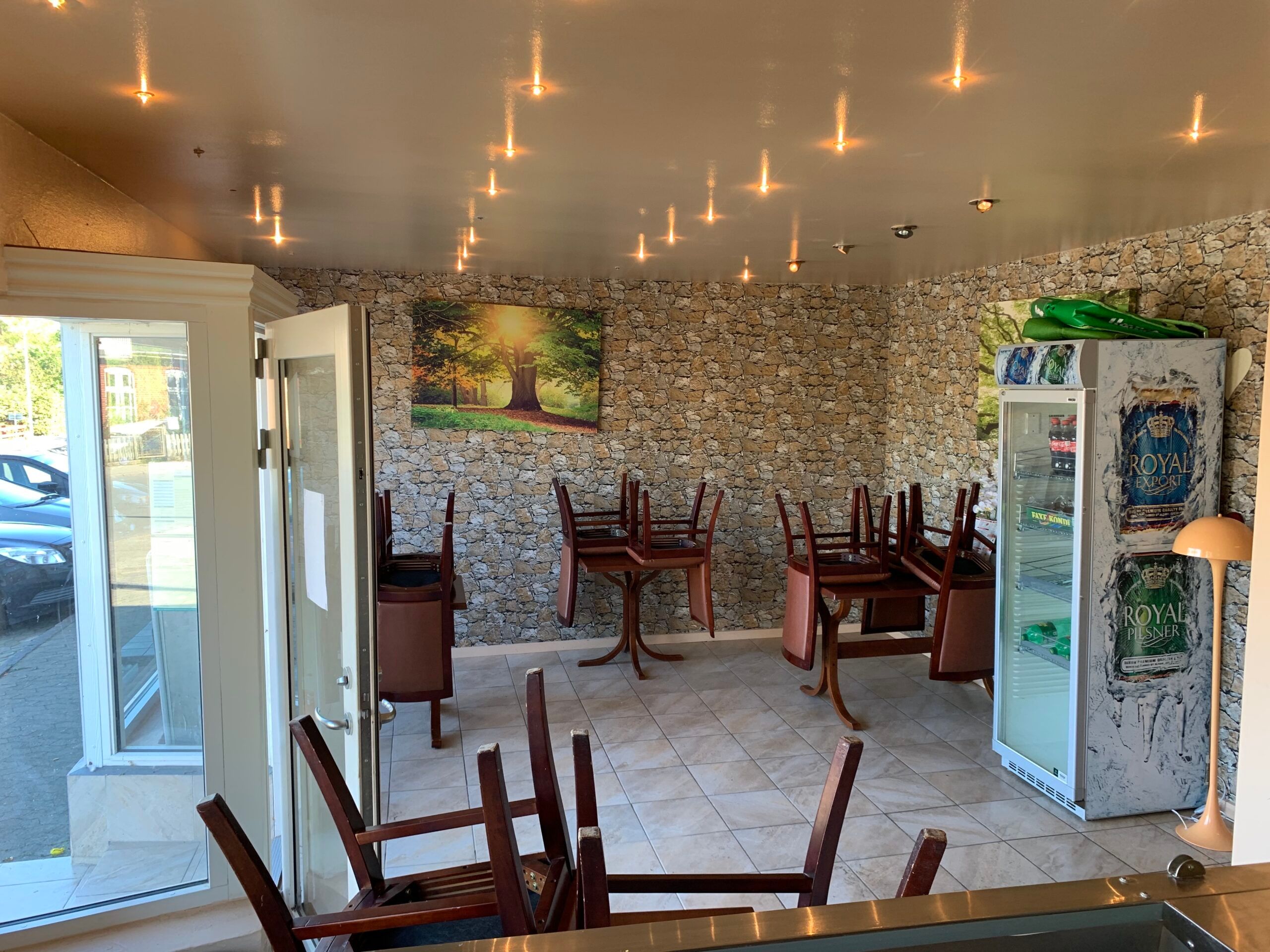 Inde i NamNami Pizza & Grill er der møbler, en stenvæg, et køleskab og en lampe.