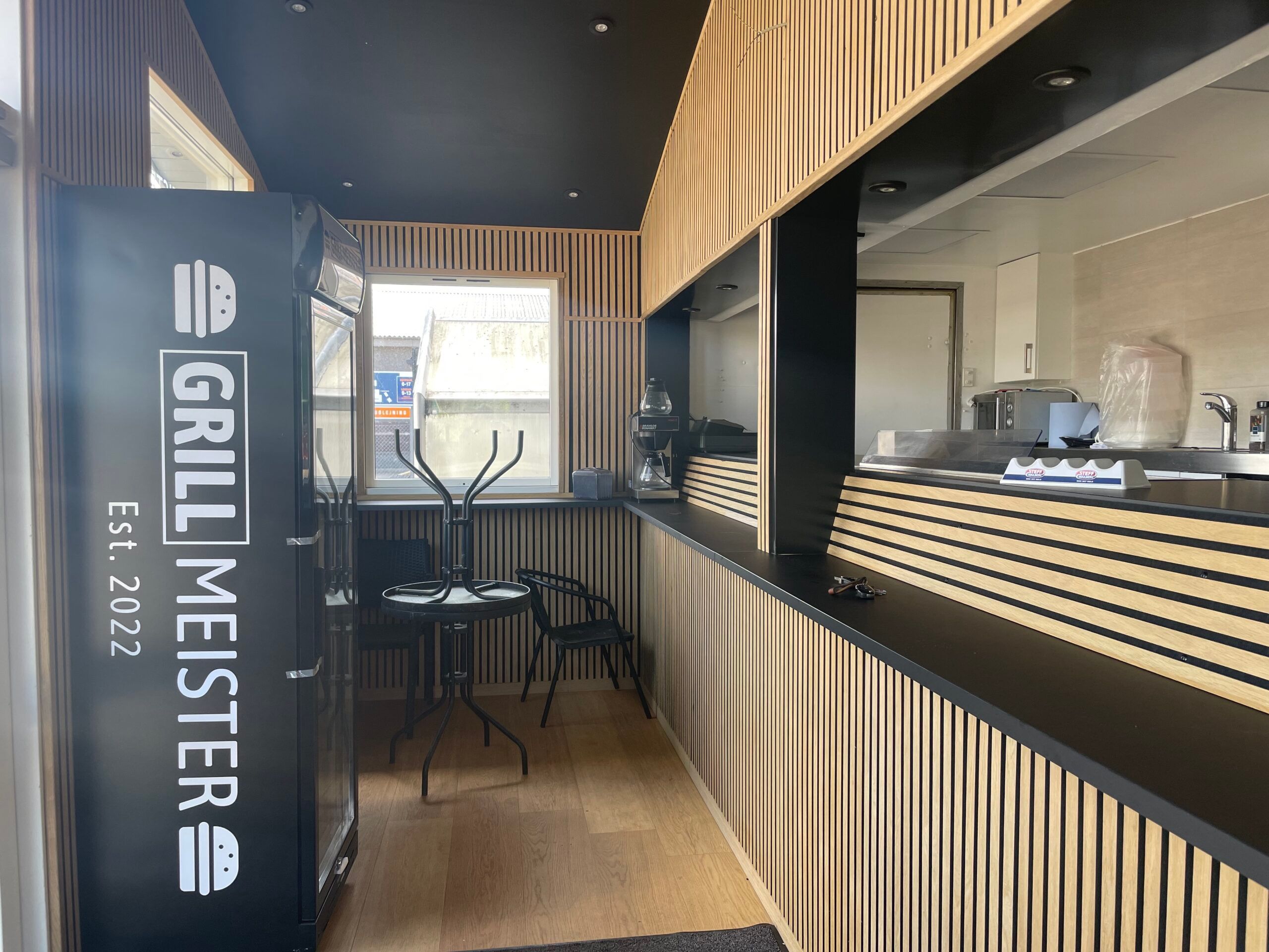 En forretningsindretning med grillmeister logo og flere møbler og apparater i det lyse lokale