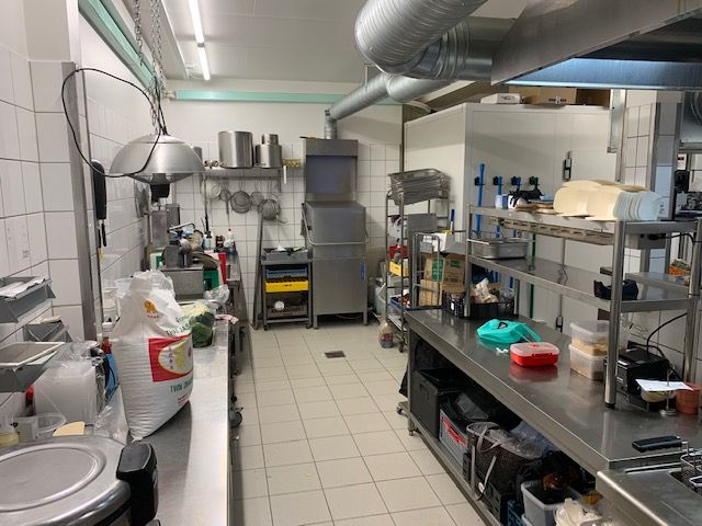 Rødhætte Thaibox er en travl thailandsk madforretning med moderne køkken og lyse gulvfliser, hvor der er flere bordplader og