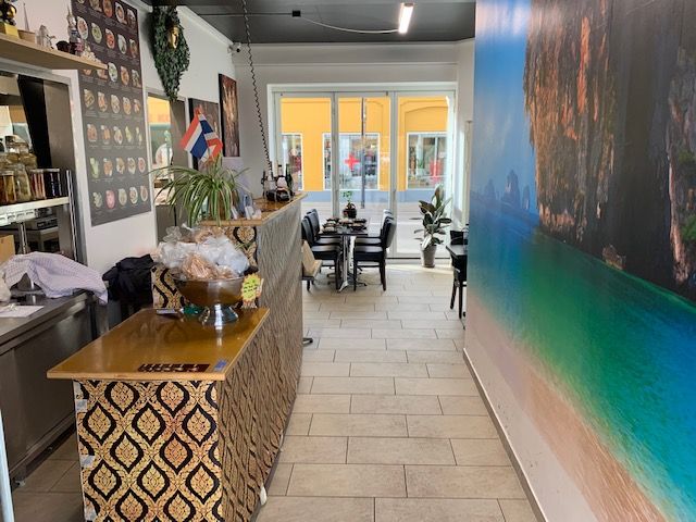 Thai restaurant i Holbæk Centrum med udendørsbord og menukort på væggen. Forretningen har en terrasse med bord og stole samt