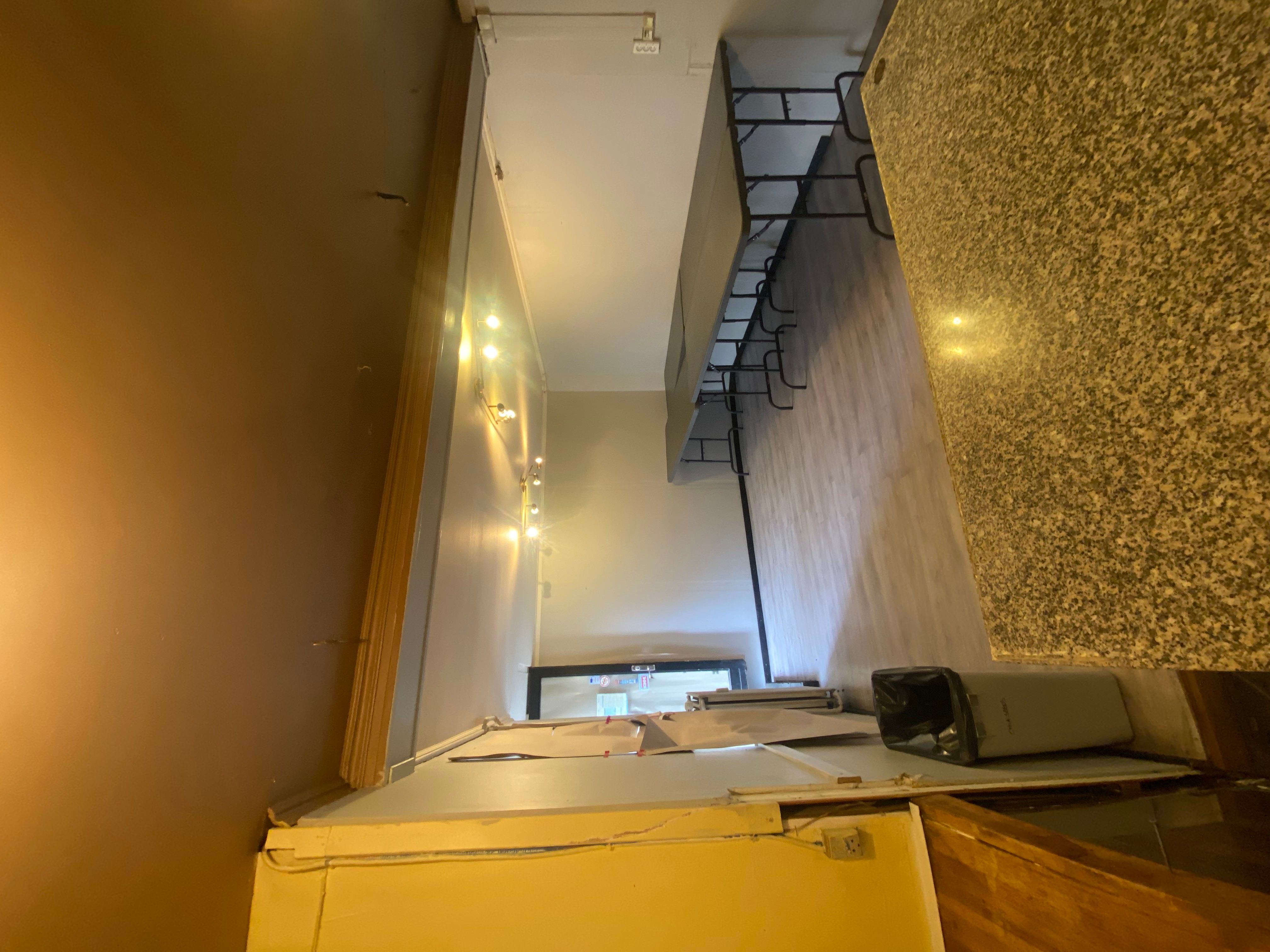 En tom og ren stue med lysegule vægge og en høj marmordisk. Der er bord og stole samt en papkasse og en støvsuger.