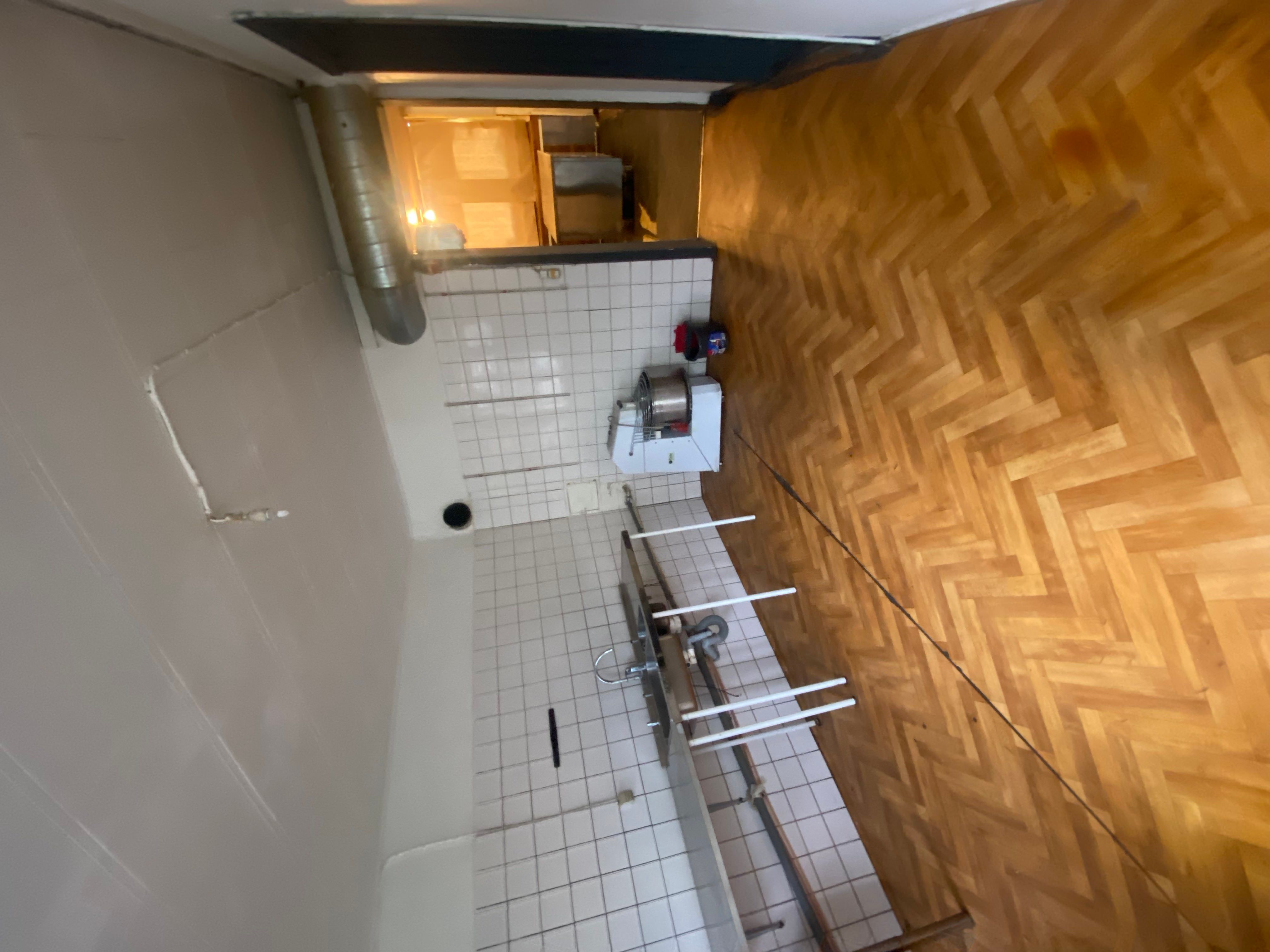 Køkken med hvide fliser og gulvtæppe og en maskine med en røgslange samt en slibemaskine og en støvsuger