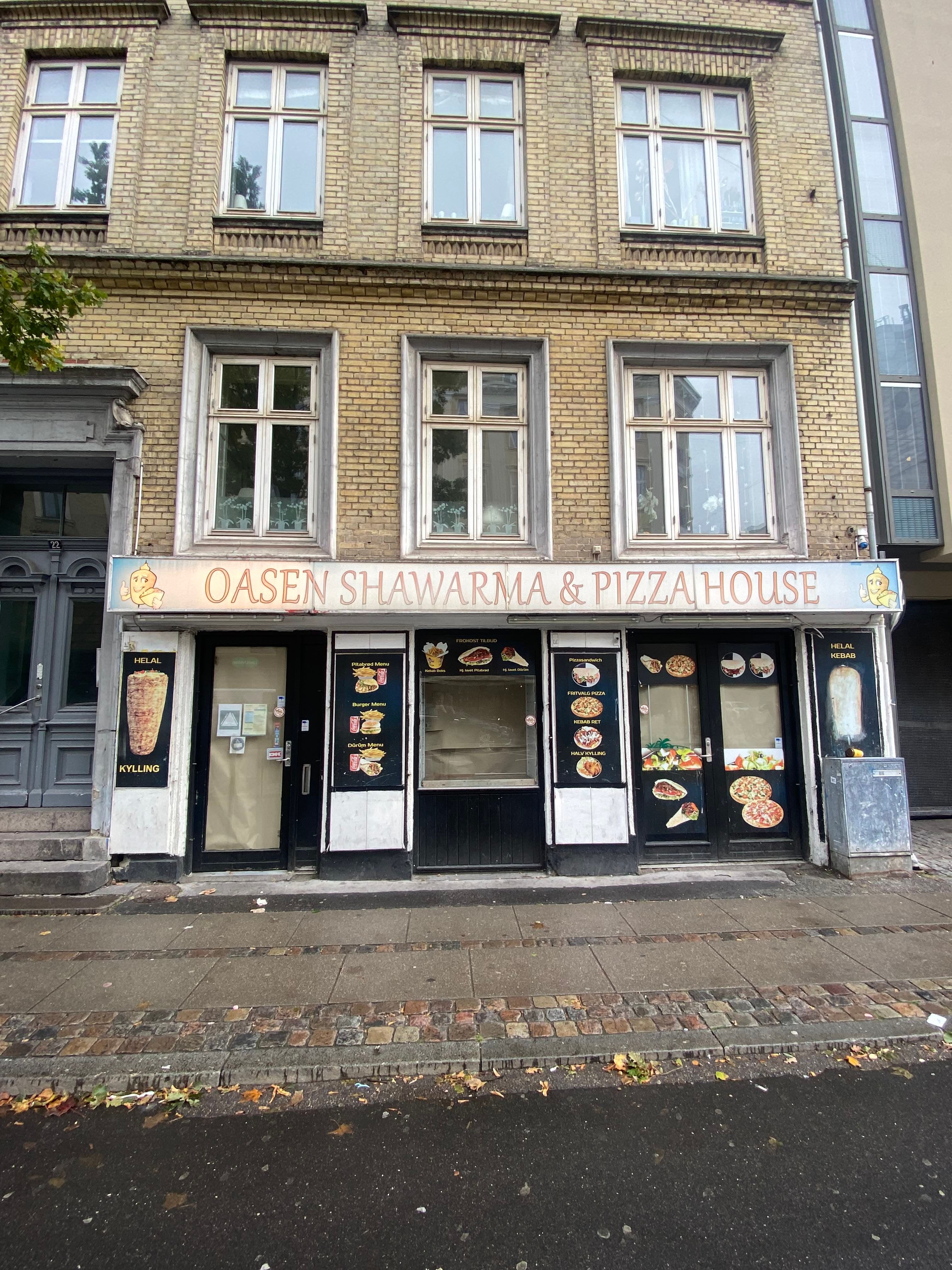 Forretningslokale med udvendig reklame for Oasen Shawarma & Pizzahouse med pizzaer og andre retter som menukort og