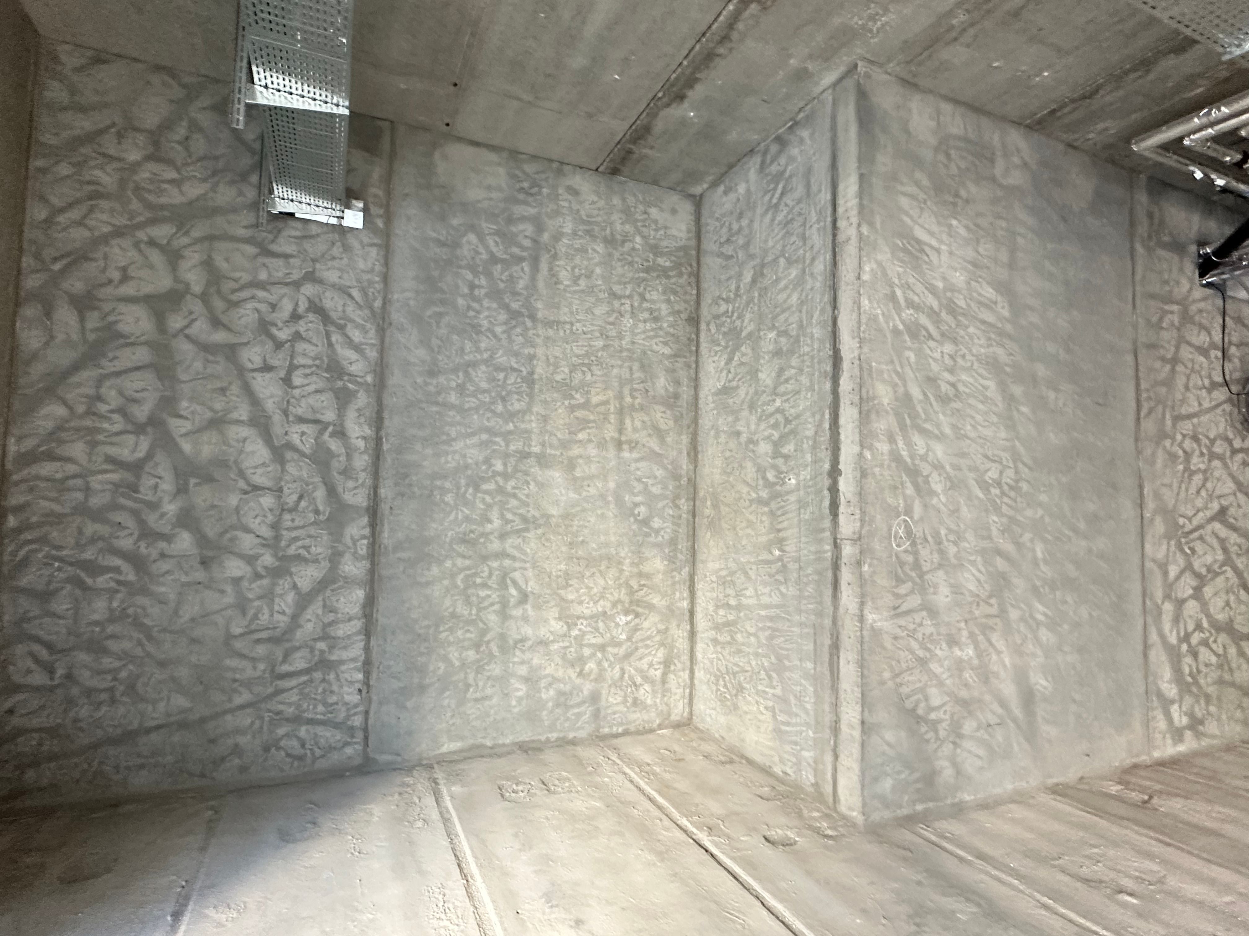 Væggene og loftet i et rum er beklædt med en hvid isolering og en krydsfinergulv er synlig