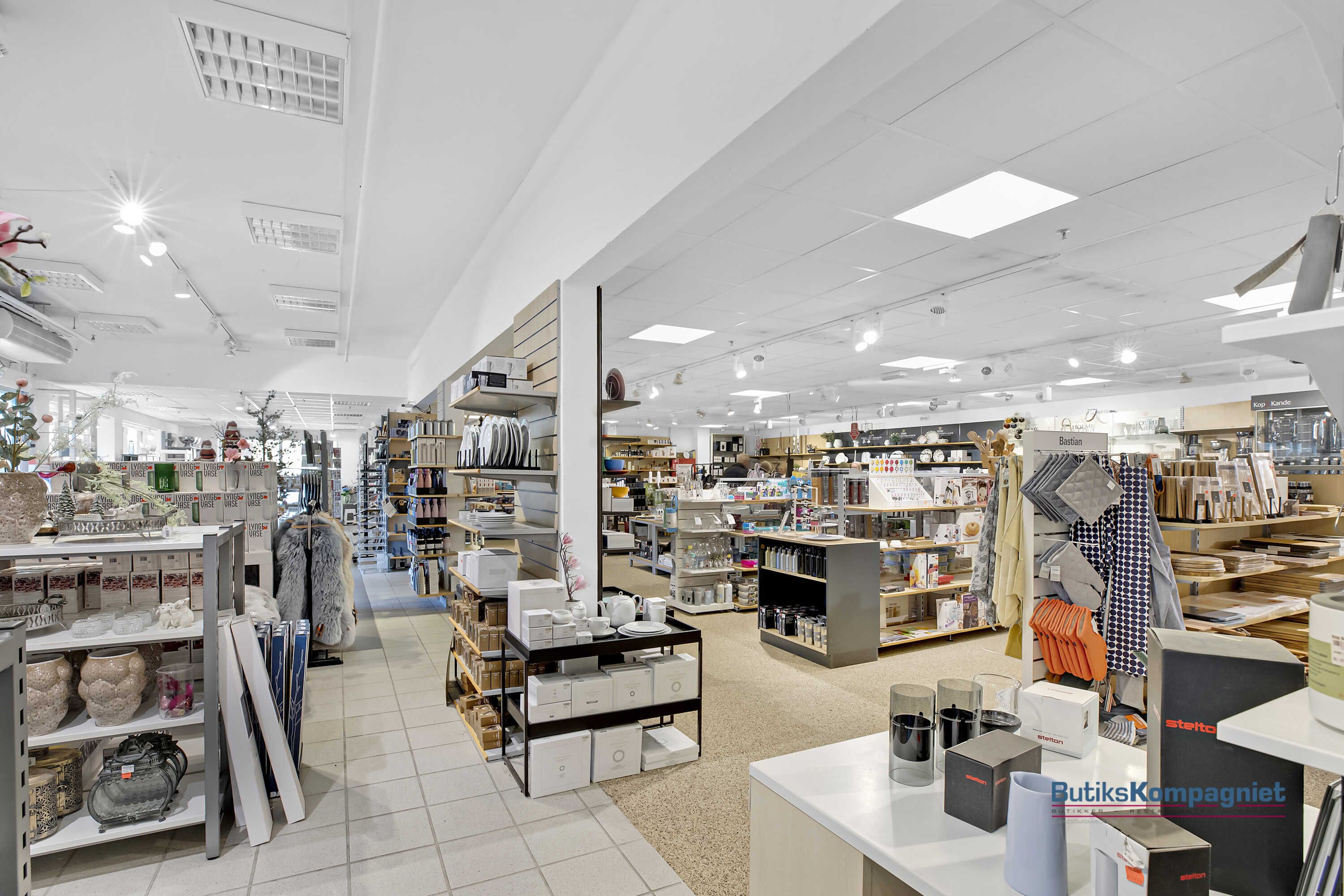 Indenfor dette store butikslokal er der store hylder med diverse produkter og tøj. På en af hylderne er der en række stelte