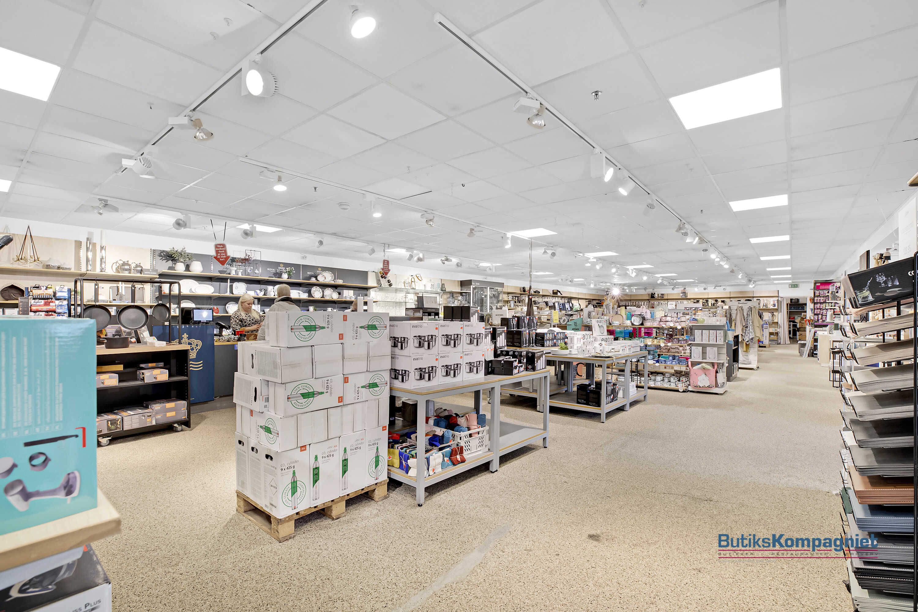 En stor forretningsforretning med køkkenartikler og møbler er oplyst med hvide loftslamper og er klar til at tage imod kunder