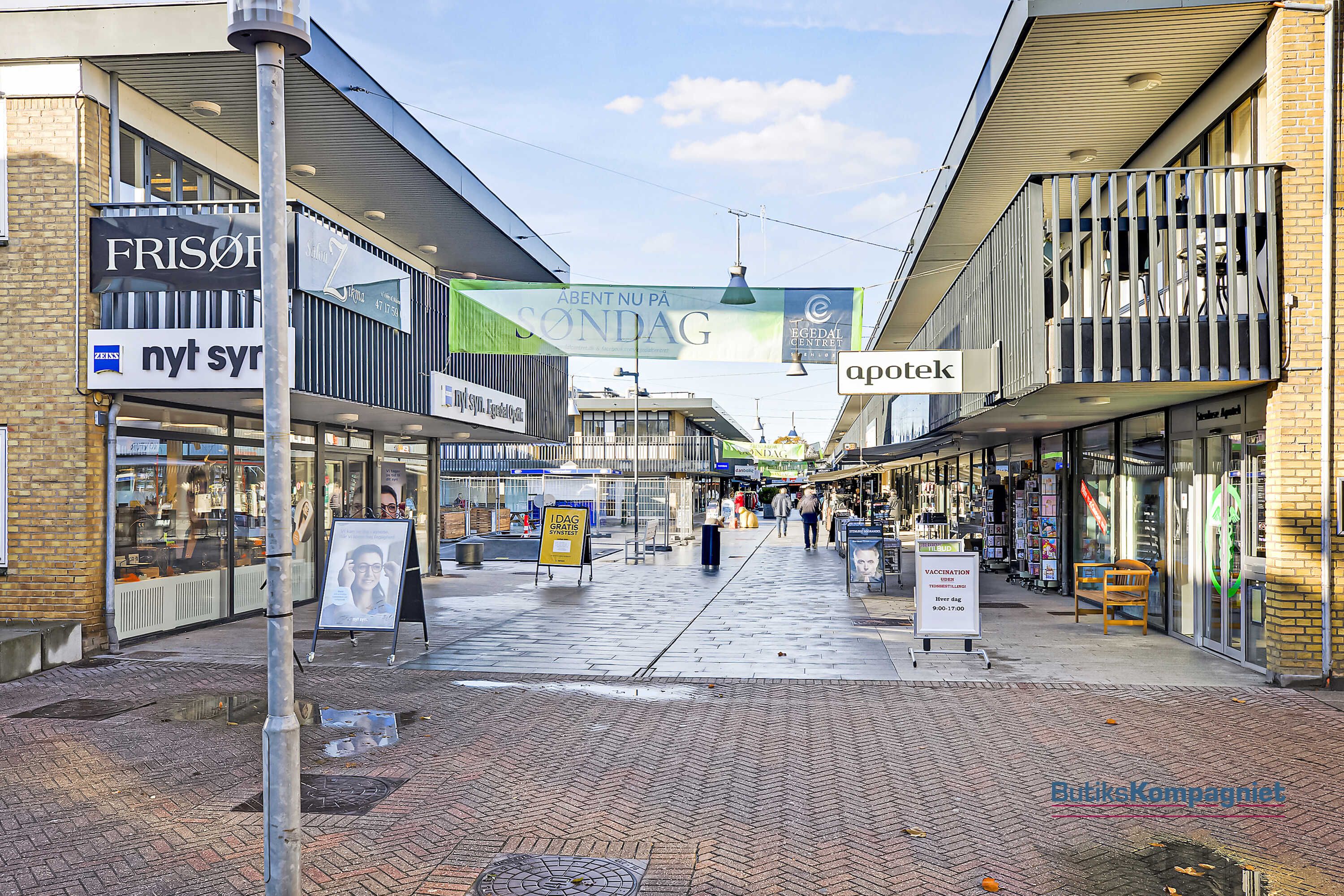 Synligt søndagsforløb i Egedalscentret med butikker, som Frisør, Nyt Syr, Apotek og flere, med en banner med teksten Abent