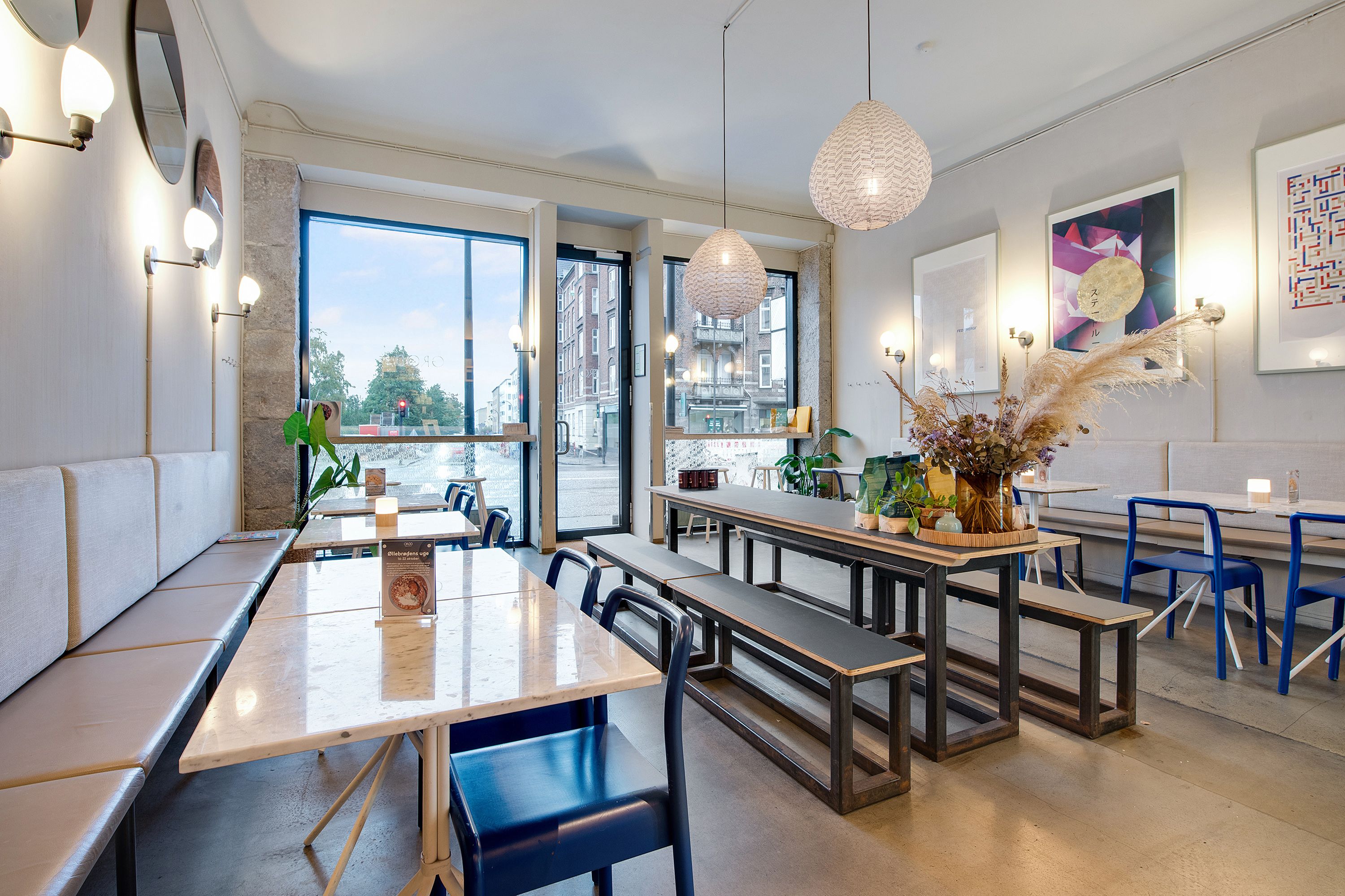 En luksuriøs restaurant med moderne interiør og lyse loftslampe, bord og stol og store vinduer mod gaden