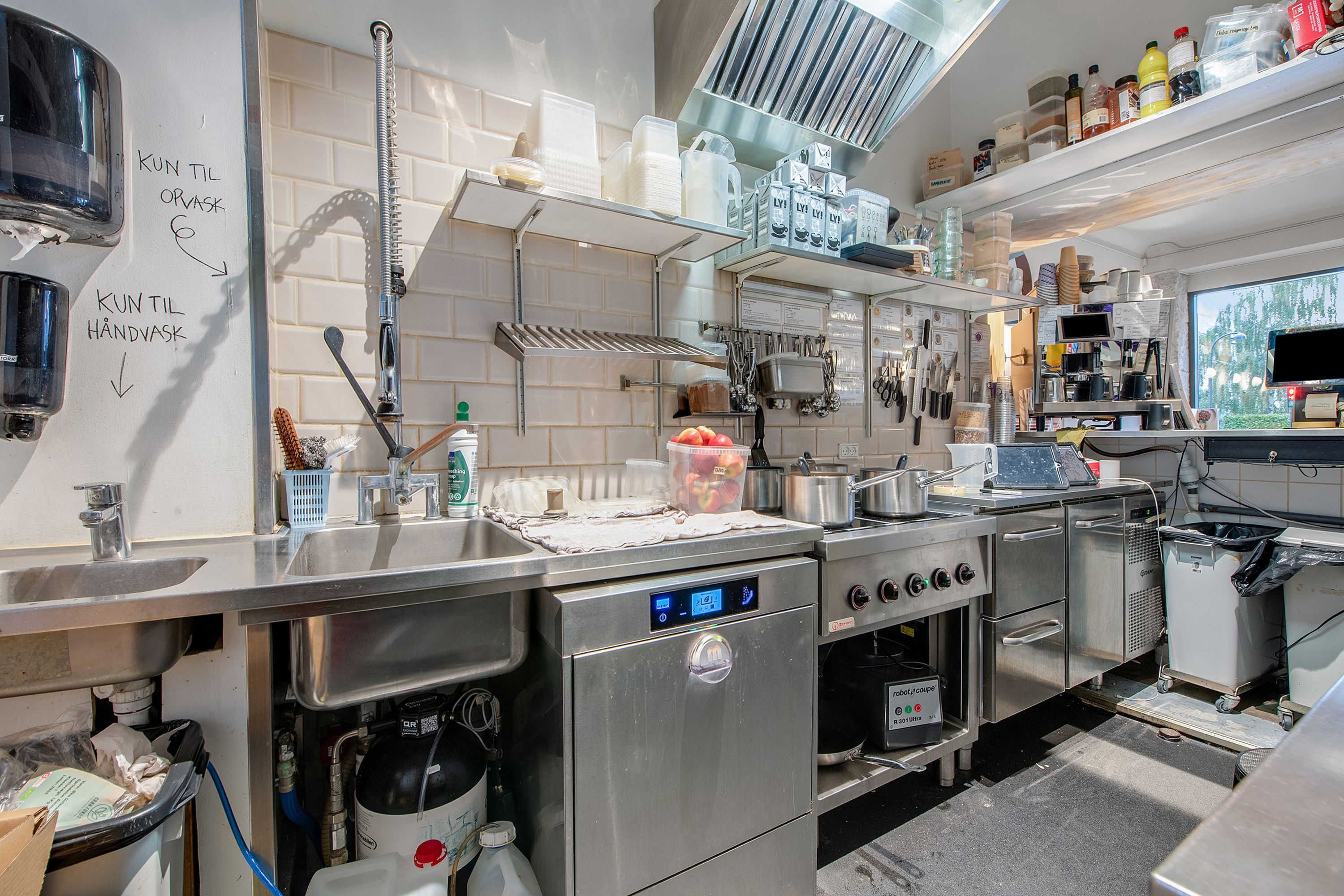 En moderne køkken med flere apparater og udstyr samt skraldele og håndvask på væggen