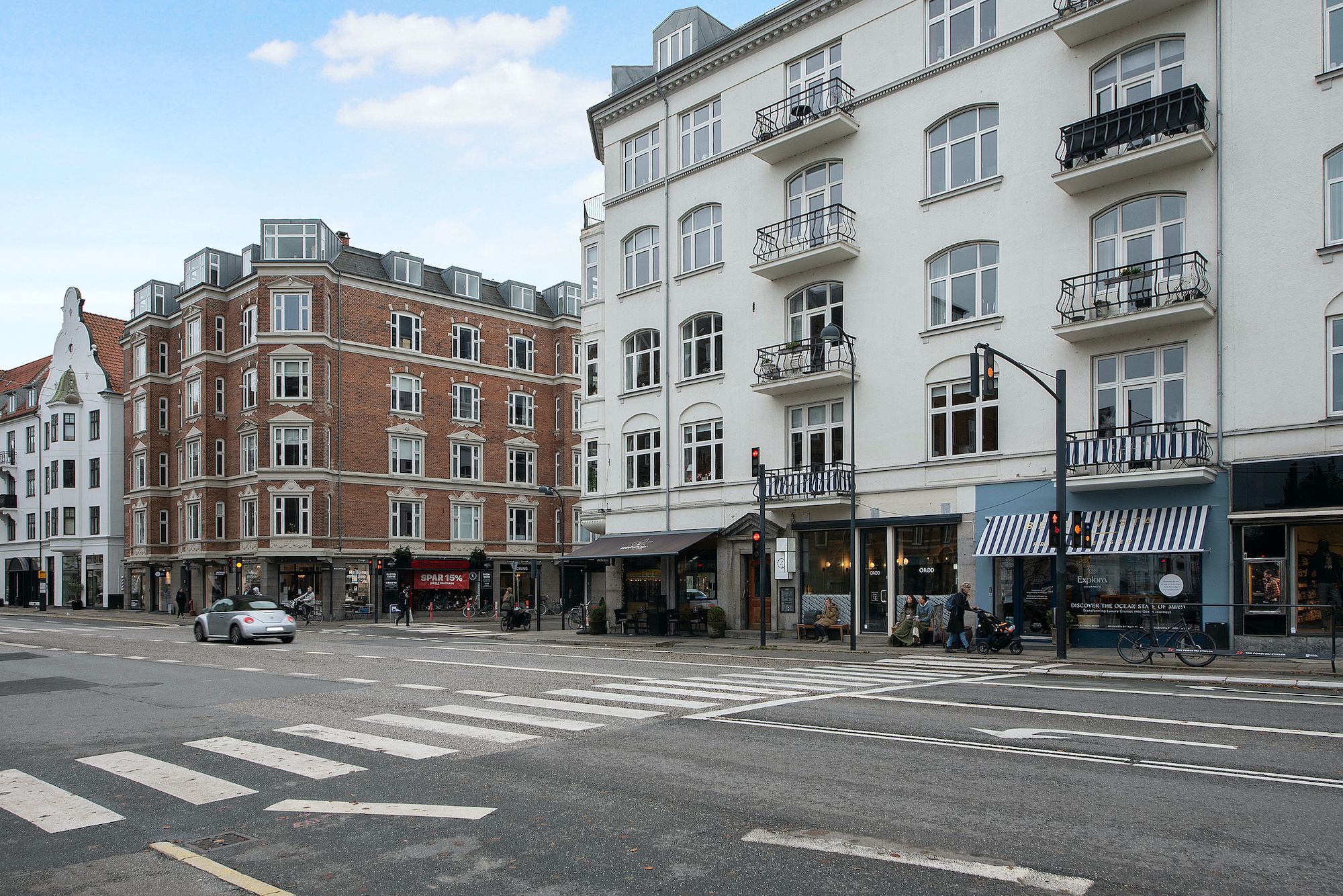 Lejlighed i lejemål i Hellerup. Strømlinede bygninger med store vinduer og balkoner. Mennesker og cykler langs fortovet.