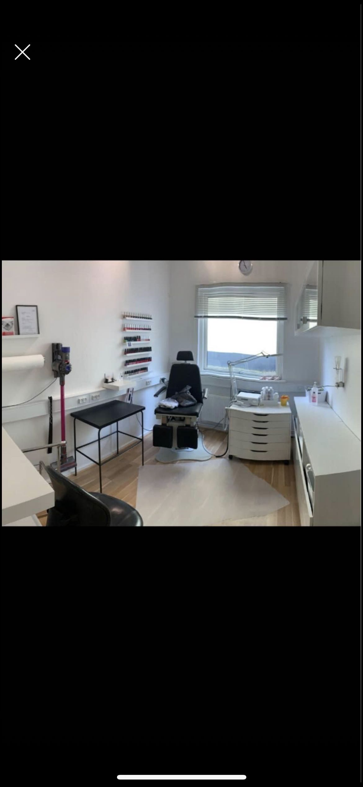 Lokale med tæppe og stol til massage i et værelse med en stol, bord og et vindue med solskin