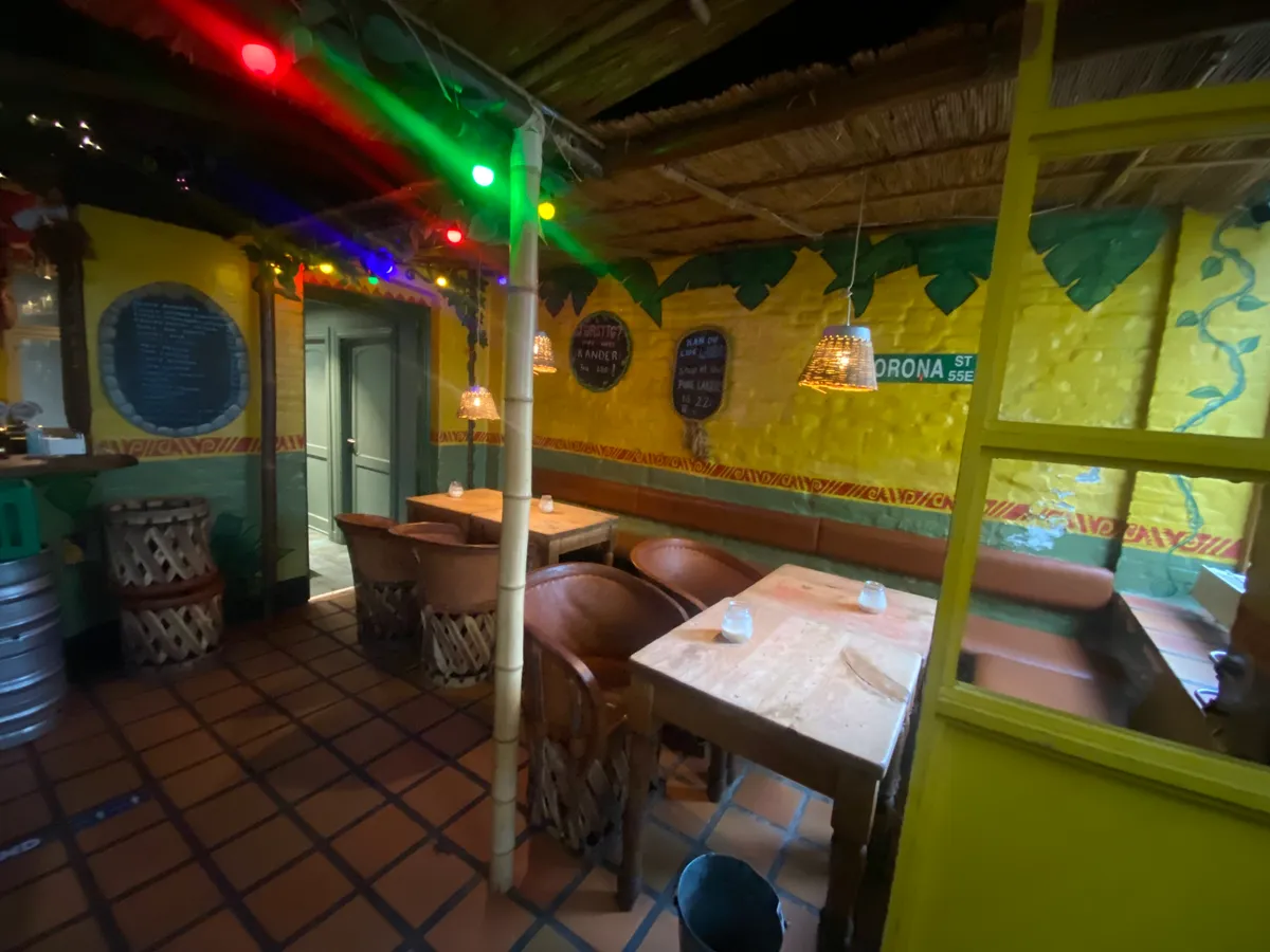 En restaurant med en stor åben dør og en gulvbelægning af fliser med møbler og en dekorativ væg med malerier