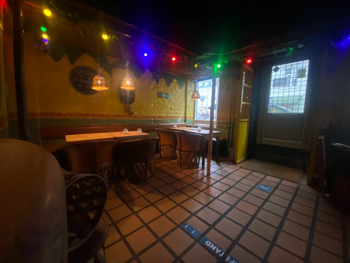 Inde i et mexicansk restaurant med møbler og dekorationer, farverige lygter og bord med kugler