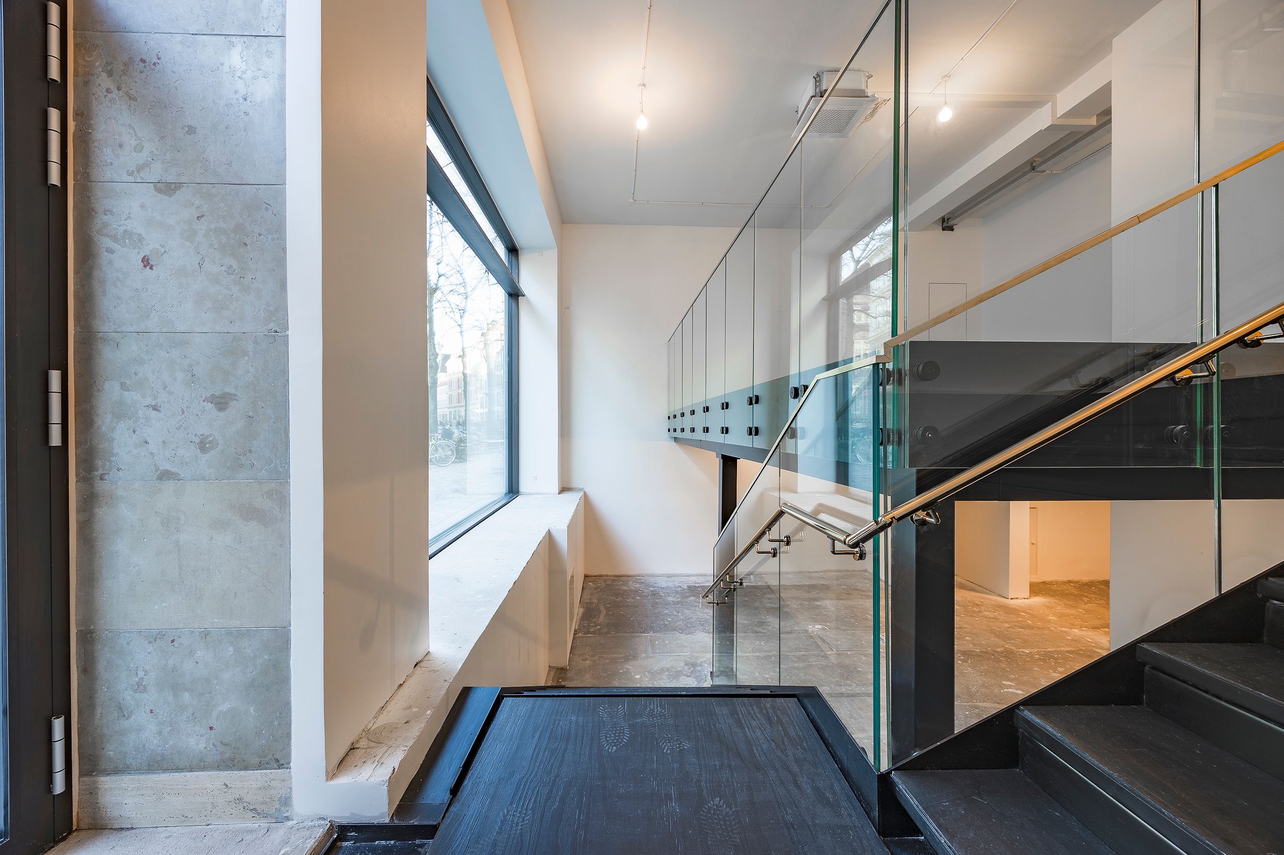 Moderne interiør med glas og sort træ i trappen og gulvet, samt lysegrå og hvide vægge