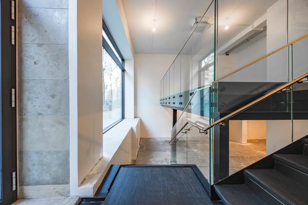 Moderne interiør med glas og sort træ i trappen og gulvet, samt lysegrå og hvide vægge