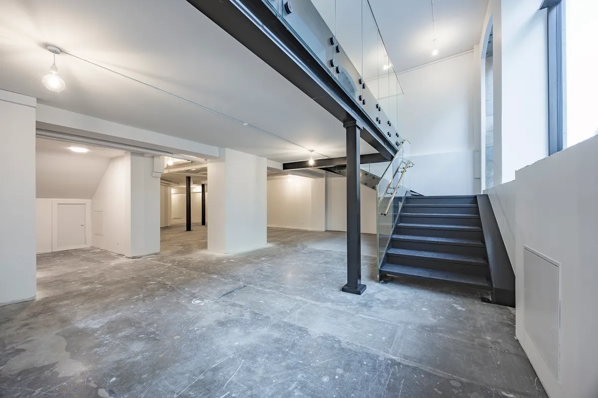 Store, moderne lokaler med glasvinduer, åbne lofter, lyse gulve og et trappeværk med sort håndtag