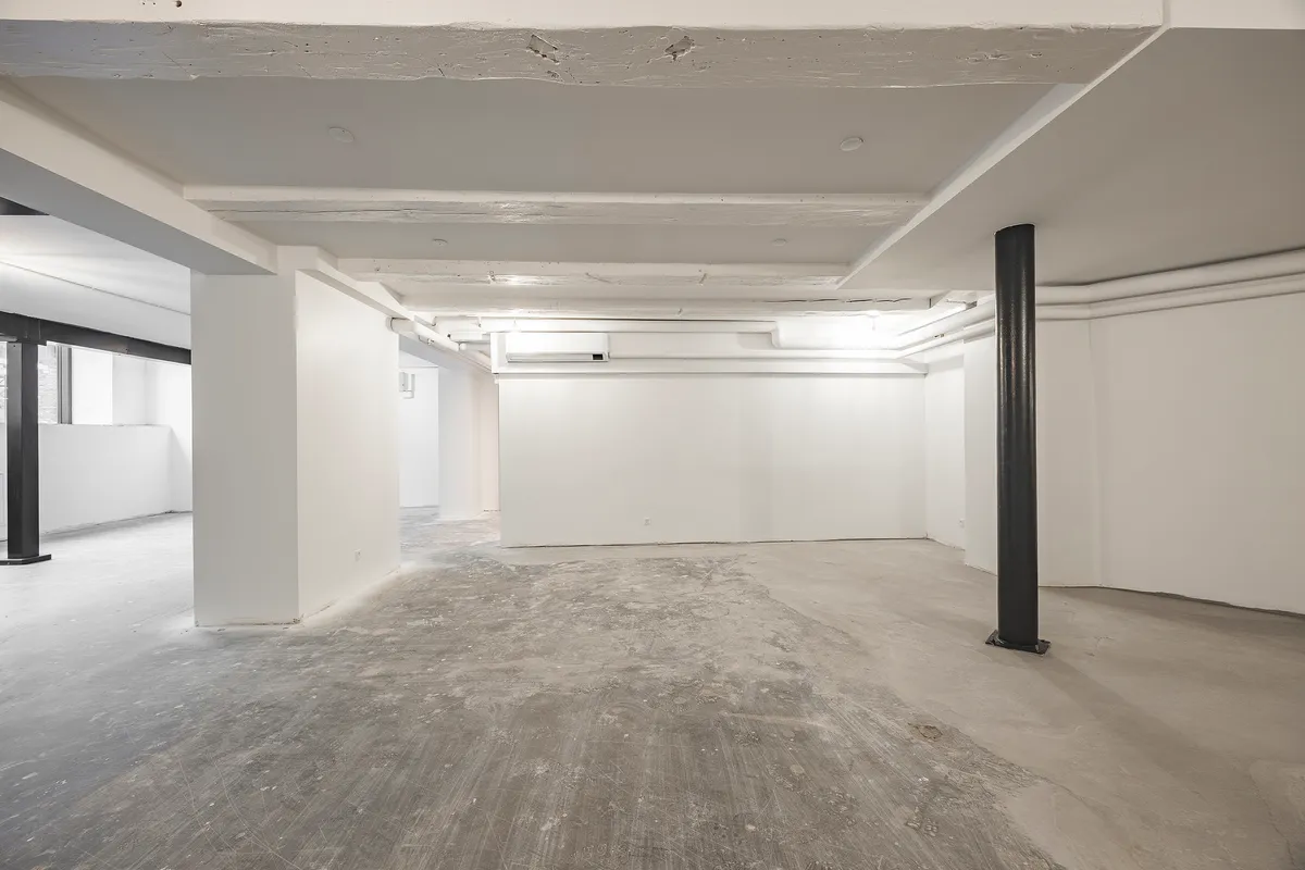 En stor, lys, industriel indretning med højt loft, hvid gulv og vægge samt to høje, sorte støtter i midten af rummet