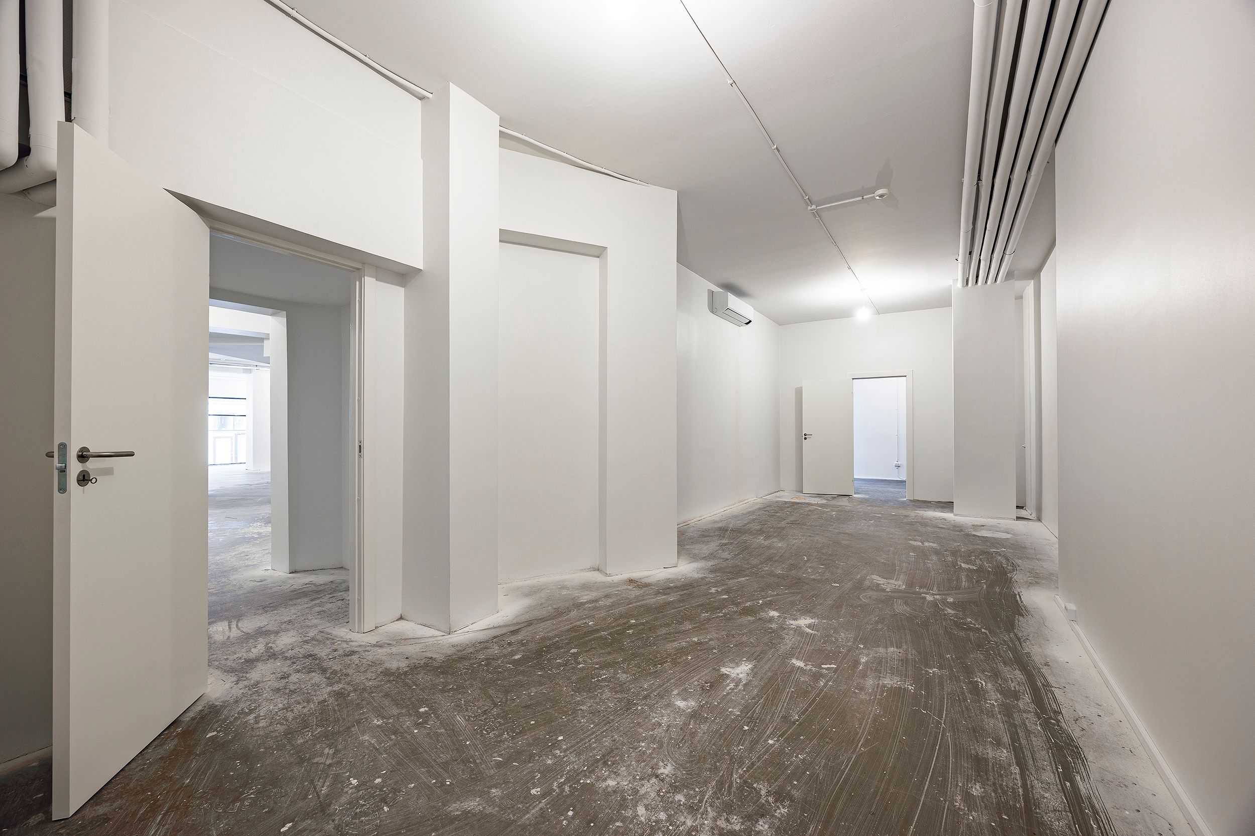 Store, hvidmalede vægge med åbne døre og tæt på tom gulv, der venter på at blive udsmykket
