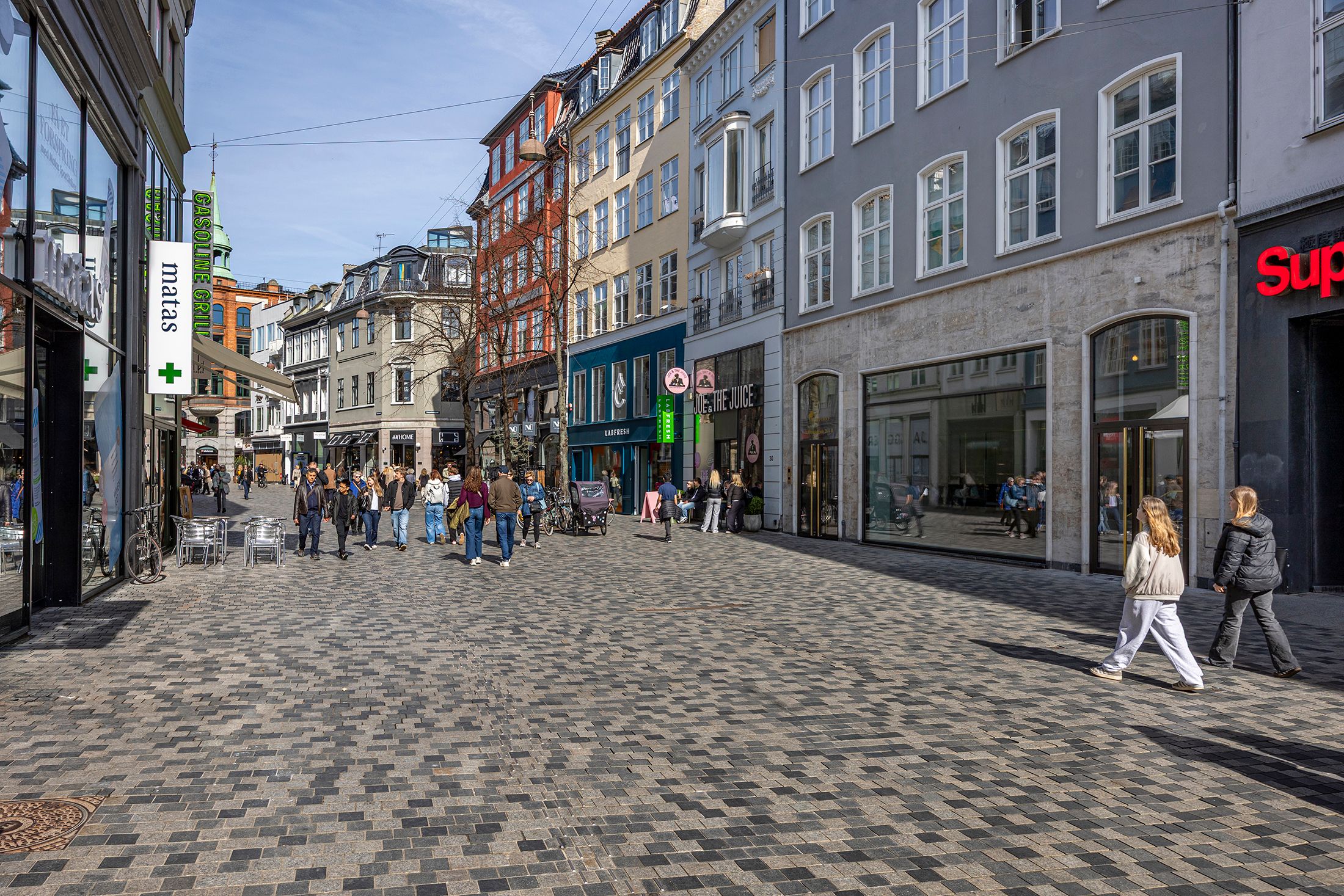 Folk går rundt på Købmagergade, som er blevet renoveret, og der er butikker med udsalg og folk, der kigger ind i vinduerne