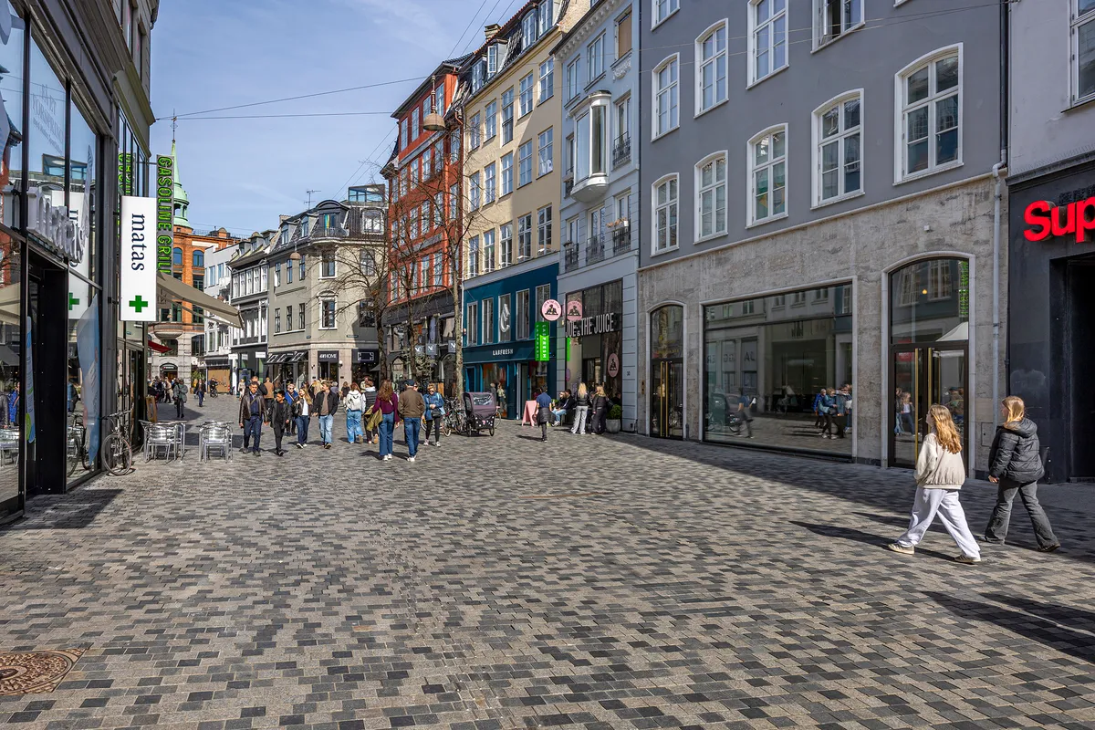 Folk går rundt på Købmagergade, som er blevet renoveret, og der er butikker med udsalg og folk, der kigger ind i vinduerne