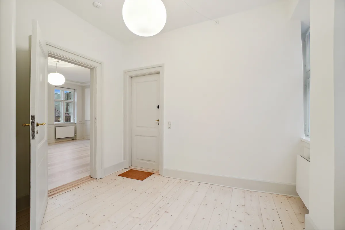 Lejlighed med højloftede værelser og massivt trægulv i lyse nuancer. Elegant lysekroner og lyse søjler. To fuldt udstyrede