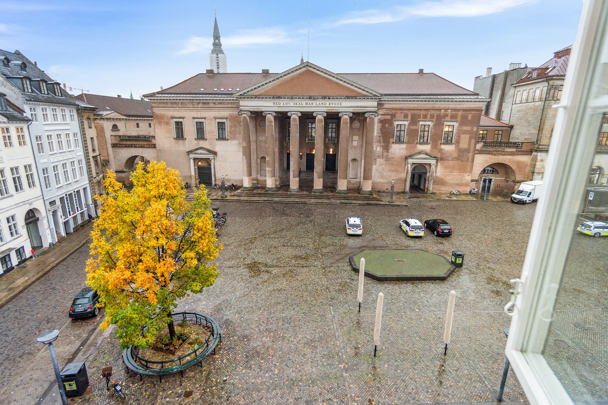 En udsigt over Nytorv med gamle bygninger og en grøn plante, Københavns Byret og parkerede biler samt cykler