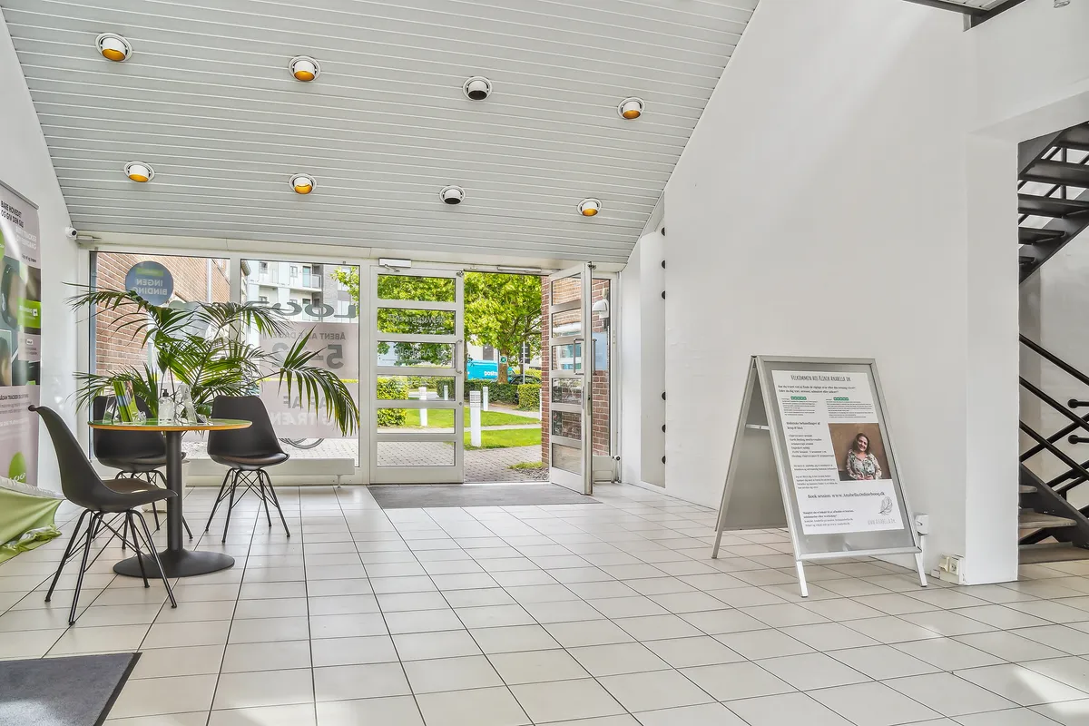 Indvends er der en indgangsdør, der fører ud til en grøn park. Værelset er lyse og ren med en bord og stole og en plakat med