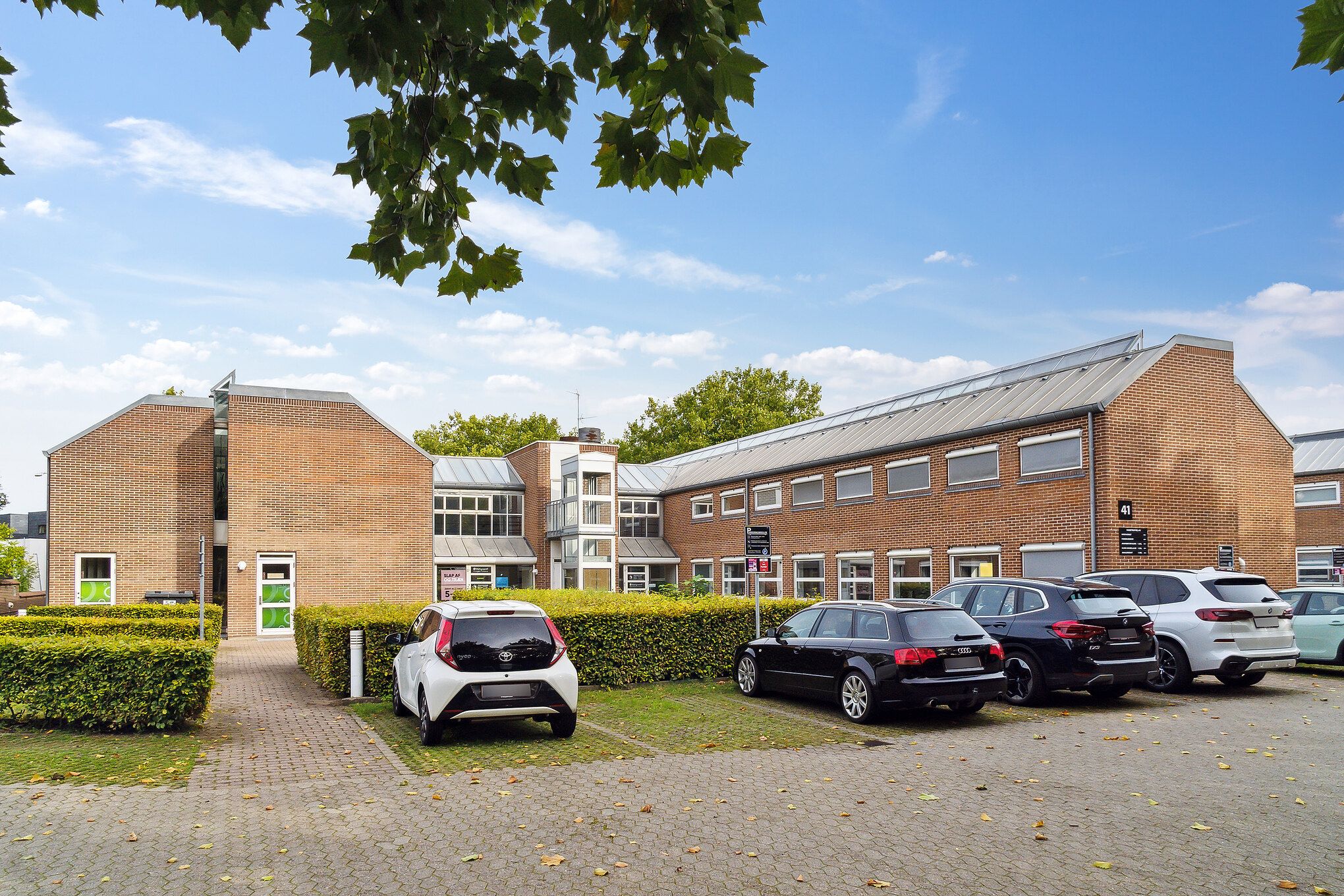 Forskudte kontorer med parkeringsplads og en Toyota og Audi parkeret og tre andre biler.
