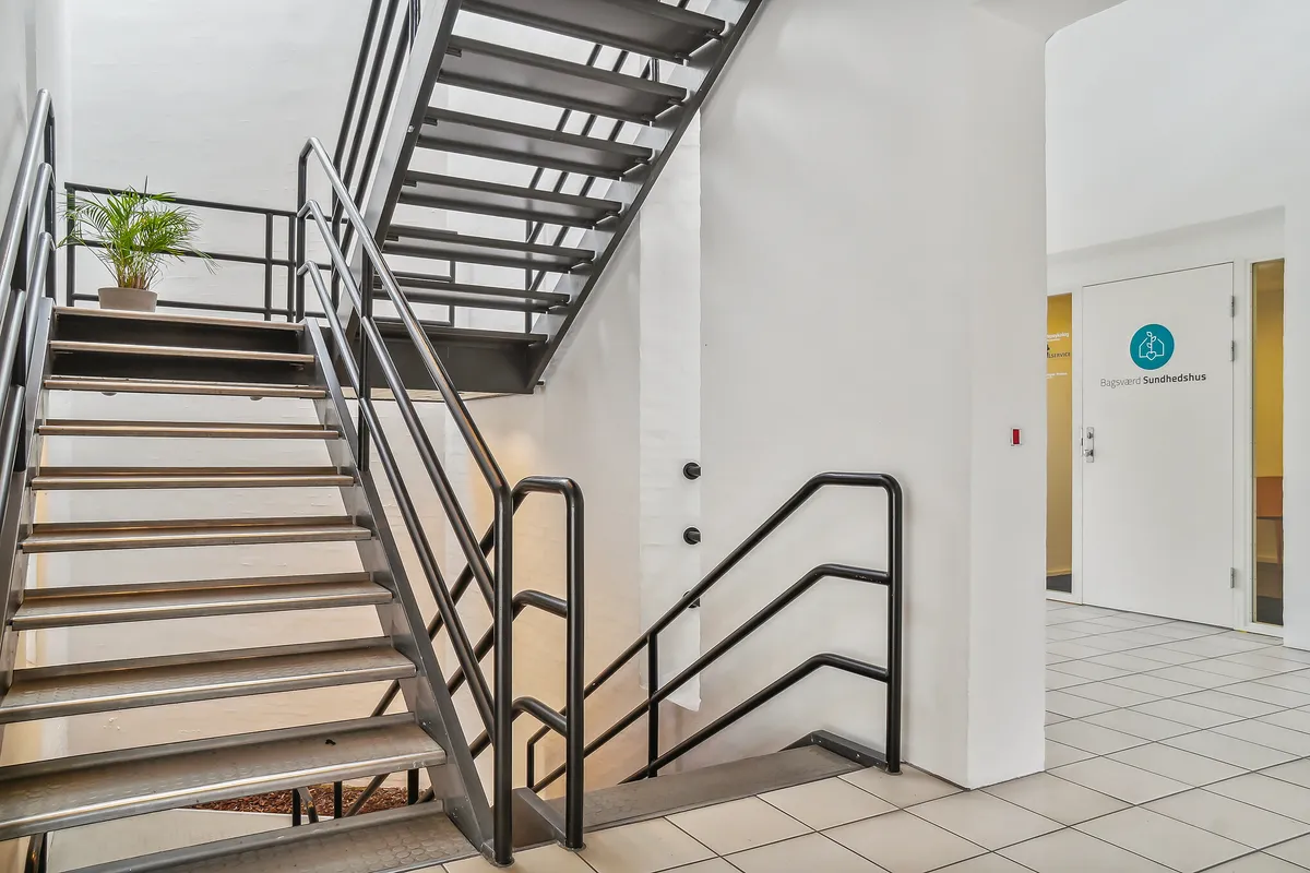 Lokaler i klinikfællesskab med skrappe stige og hvide vægge og døre. Der er et gulv med hvide kakler og en dør med teksten