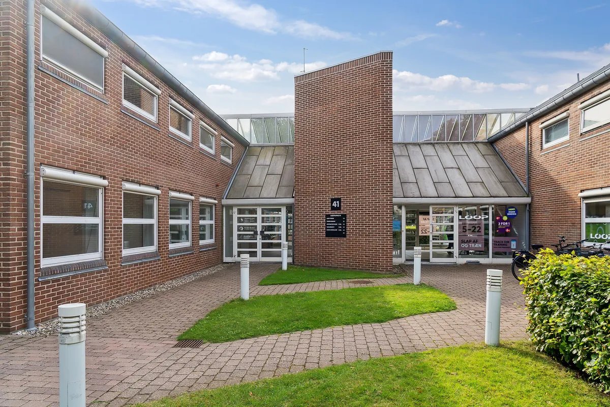 Lokaler i klinikfællesskab med enkeltindgang og nummerplade 41. Her er slette græsplæner, bollarder og to parkerede cykler.