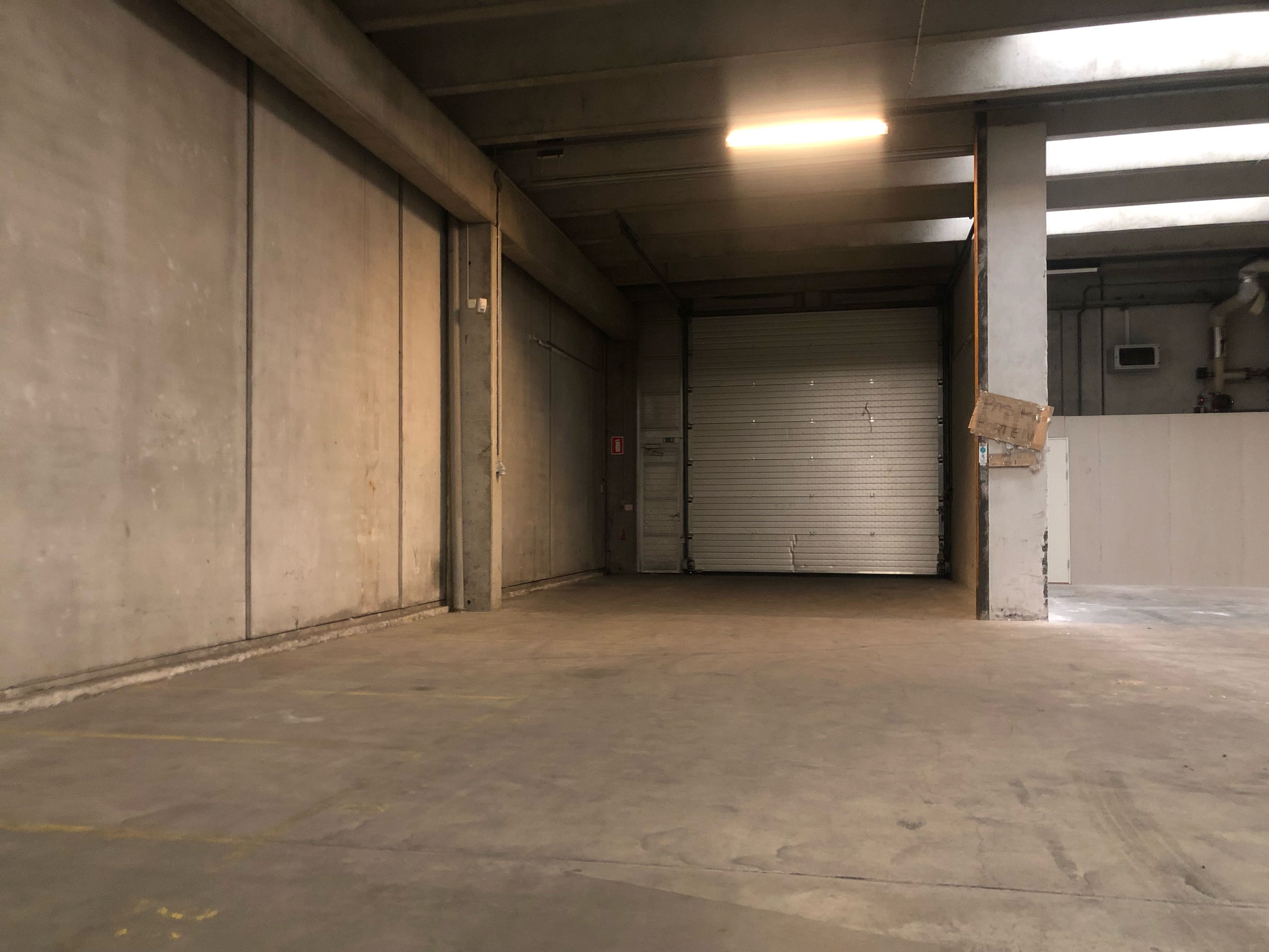 Lagerlejemål med lukket garagedør og stærke vægge i et stort og tomt rum med højt til loftet
