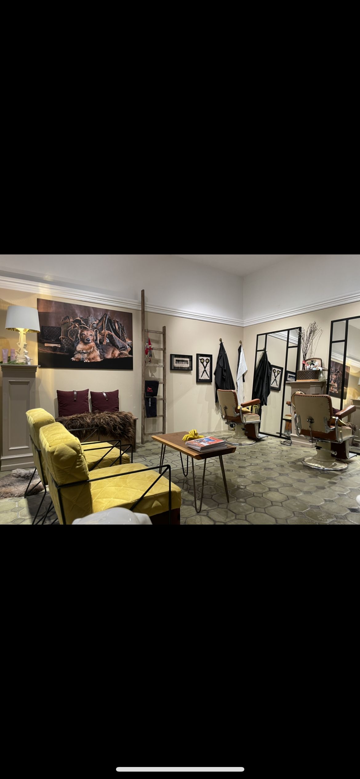 Et sælgerrum med gulv i hexagonmønster og lysegul sofa og to stole med en lænestol og to barberstole bagtil