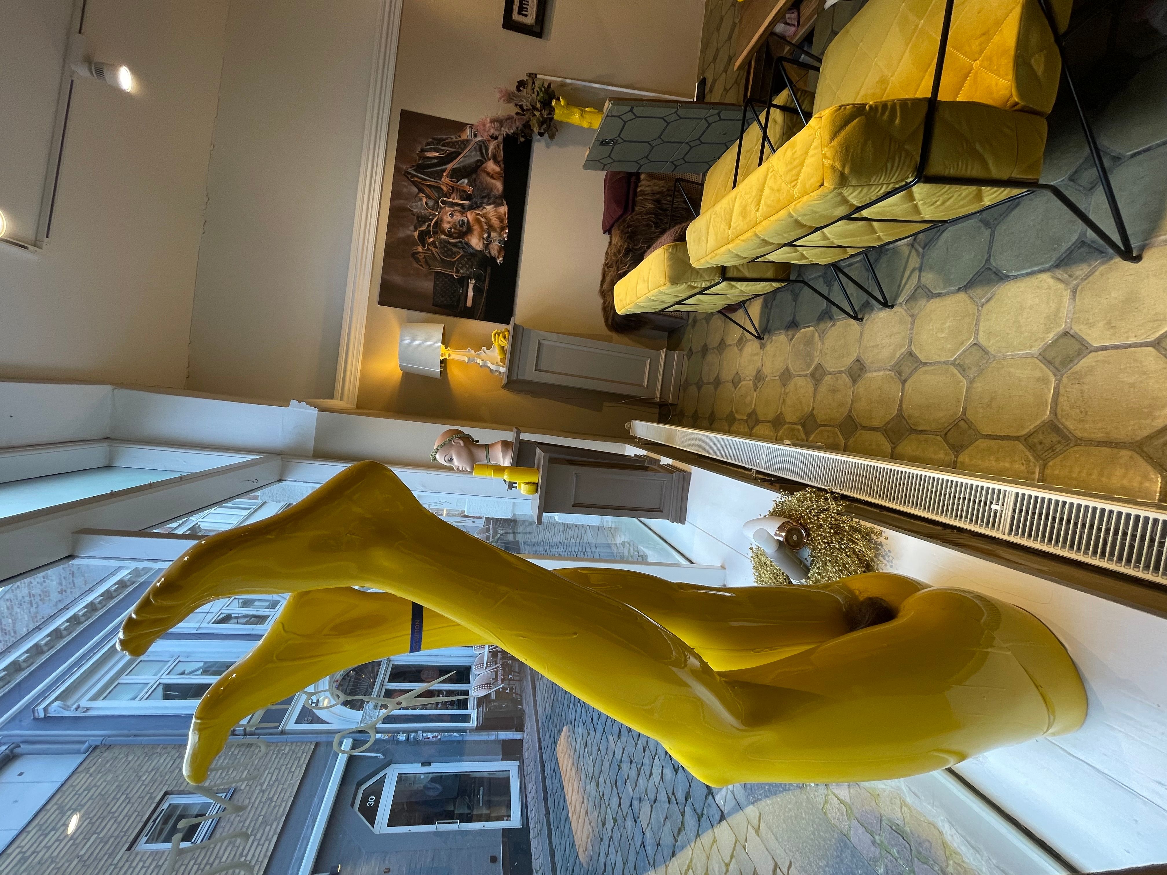 Et stort gult skulptur og en sofa i gult og sort i et smukt interiør med lysegule vægge