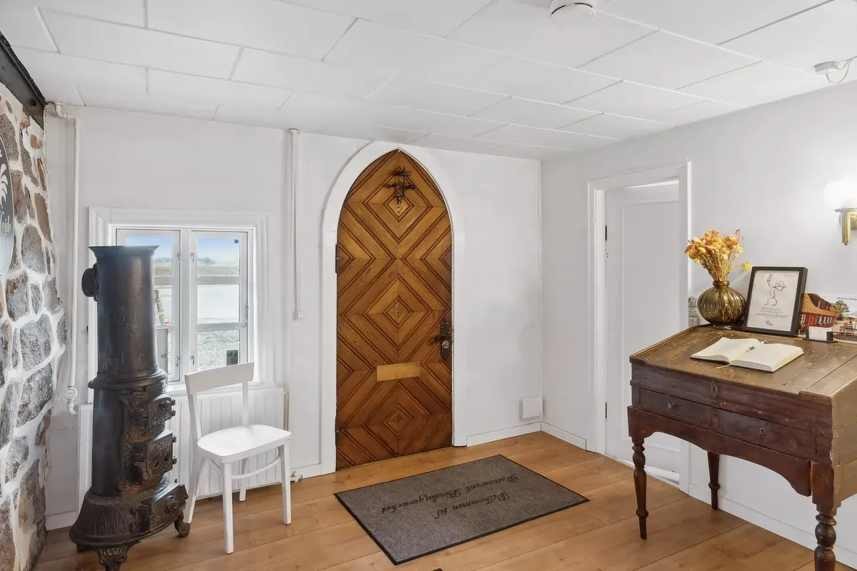 Hjørne med høj gulvbeklædning og en antik, træ og metal skrivebord med blomster og bog på bordet