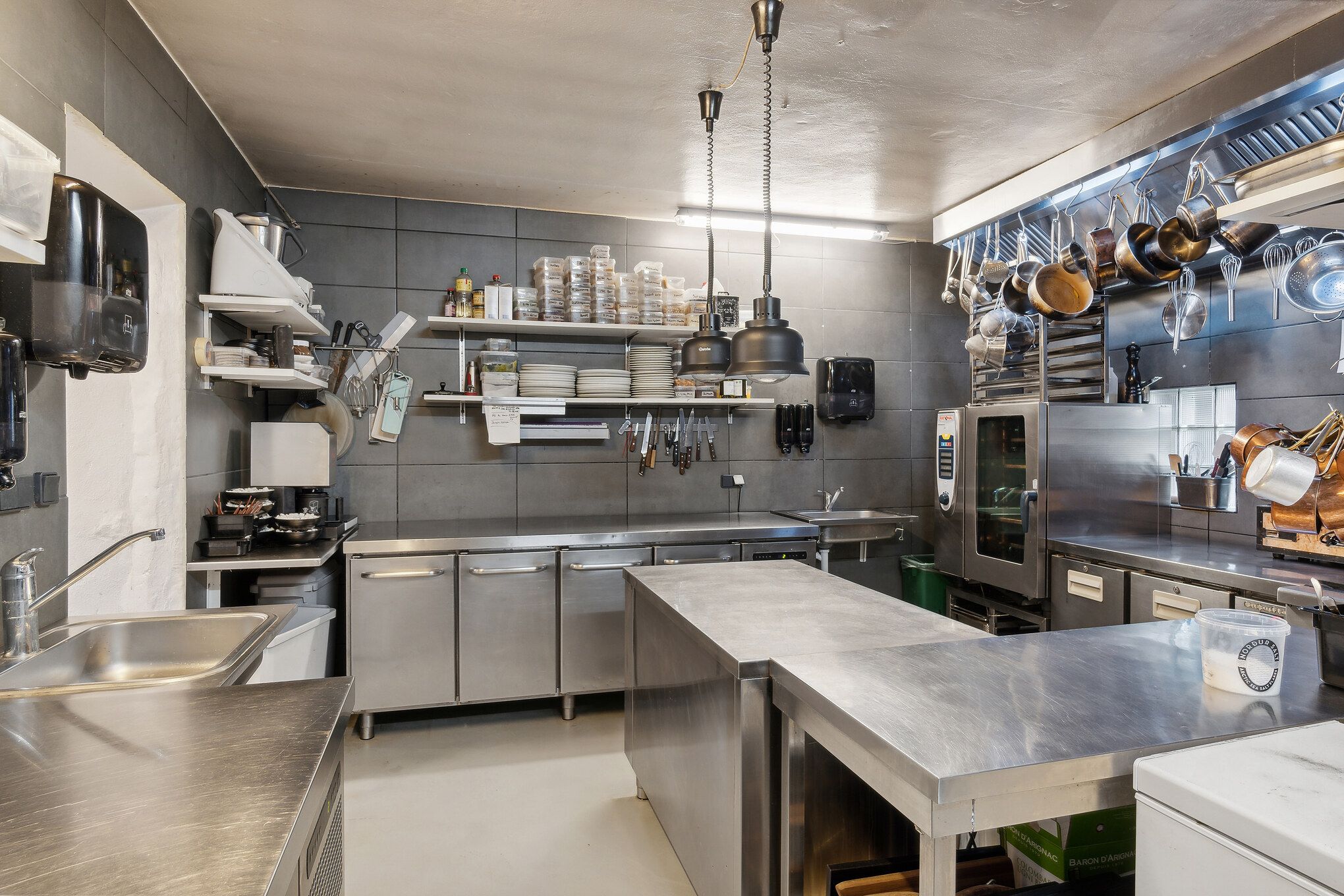 En stor kommerciel køkken med store metalborde, store ovne og masser af udstyret i en kommerciel køkken.