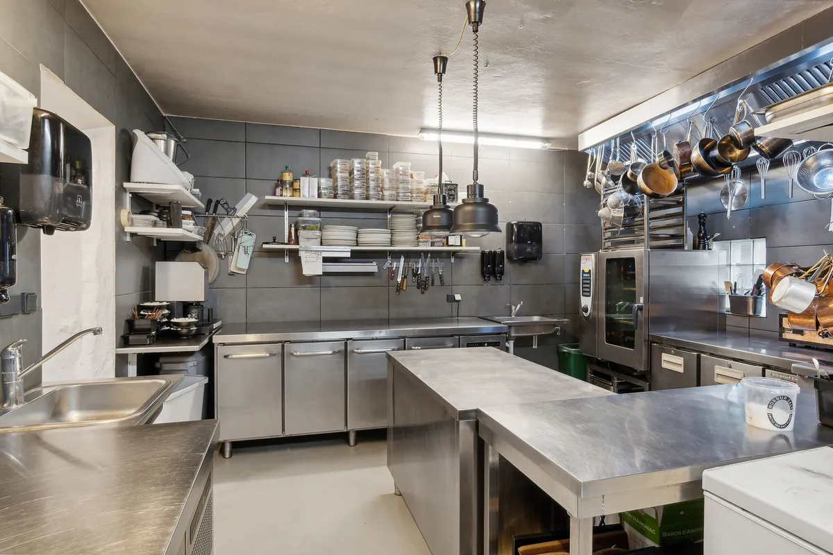 En stor kommerciel køkken med store metalborde, store ovne og masser af udstyret i en kommerciel køkken.