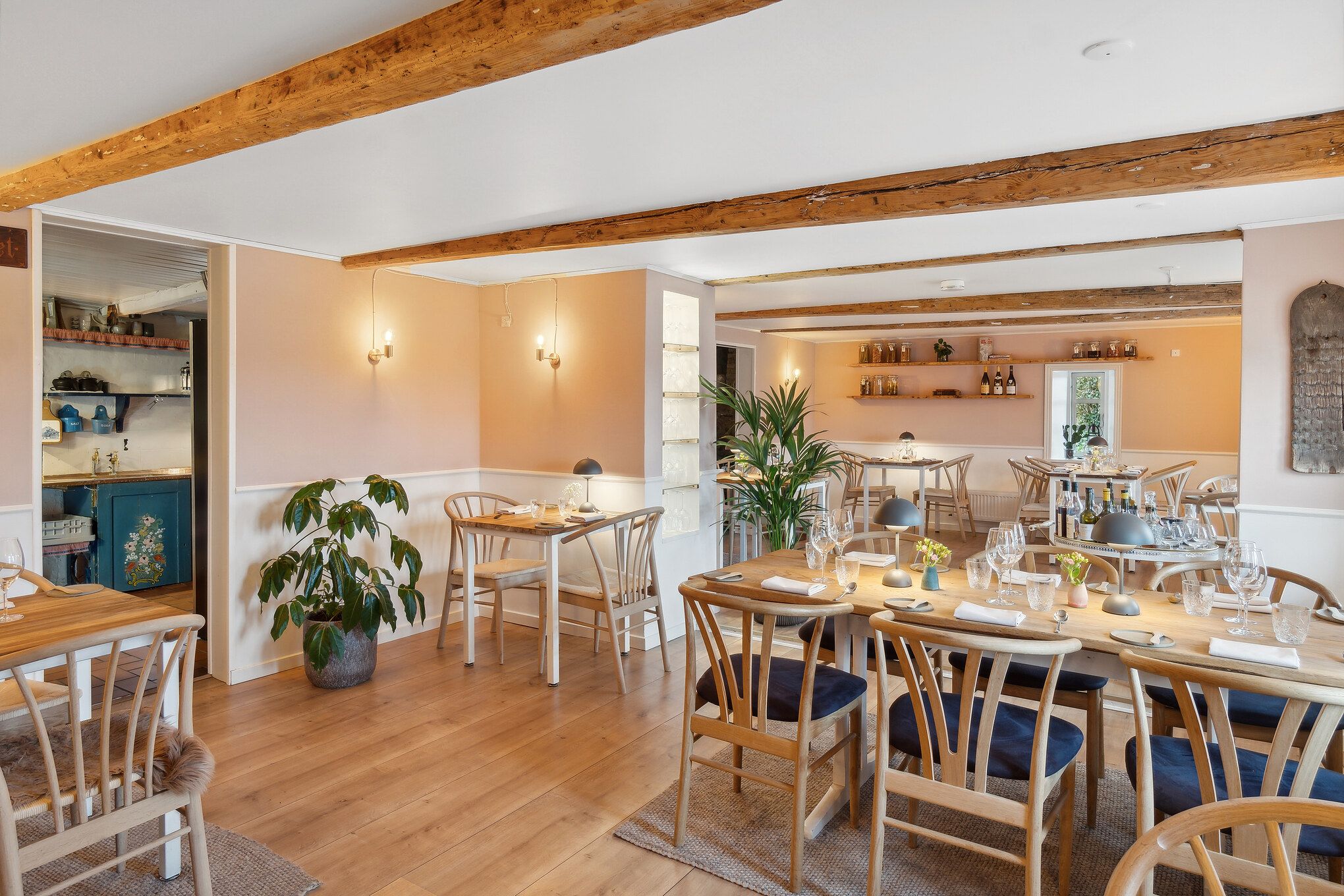 Hyggeligt spisestue med lyse træmøbler, store vinduer og en elegant indretning, der skaber et hyggeligt og indbydende