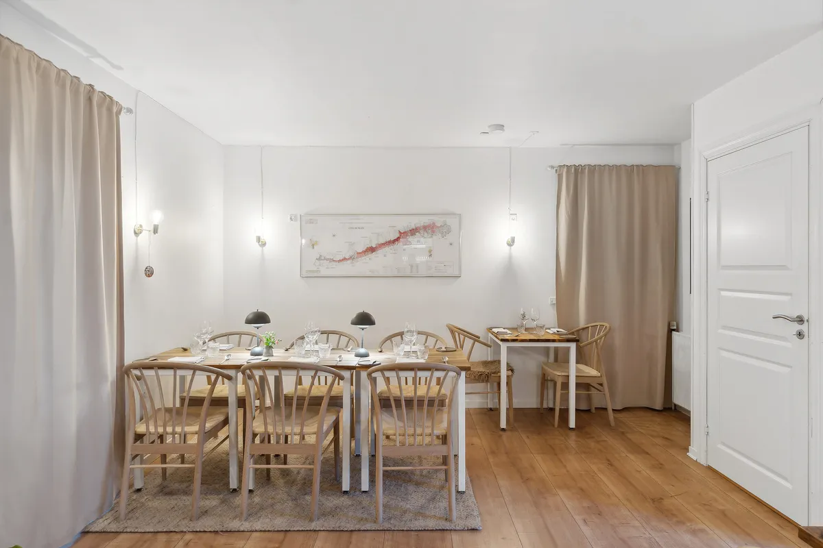 Foto af et køkken med en stor spisebord, otte stole og et sæt vinglas og krystaller og en lampe på bordet