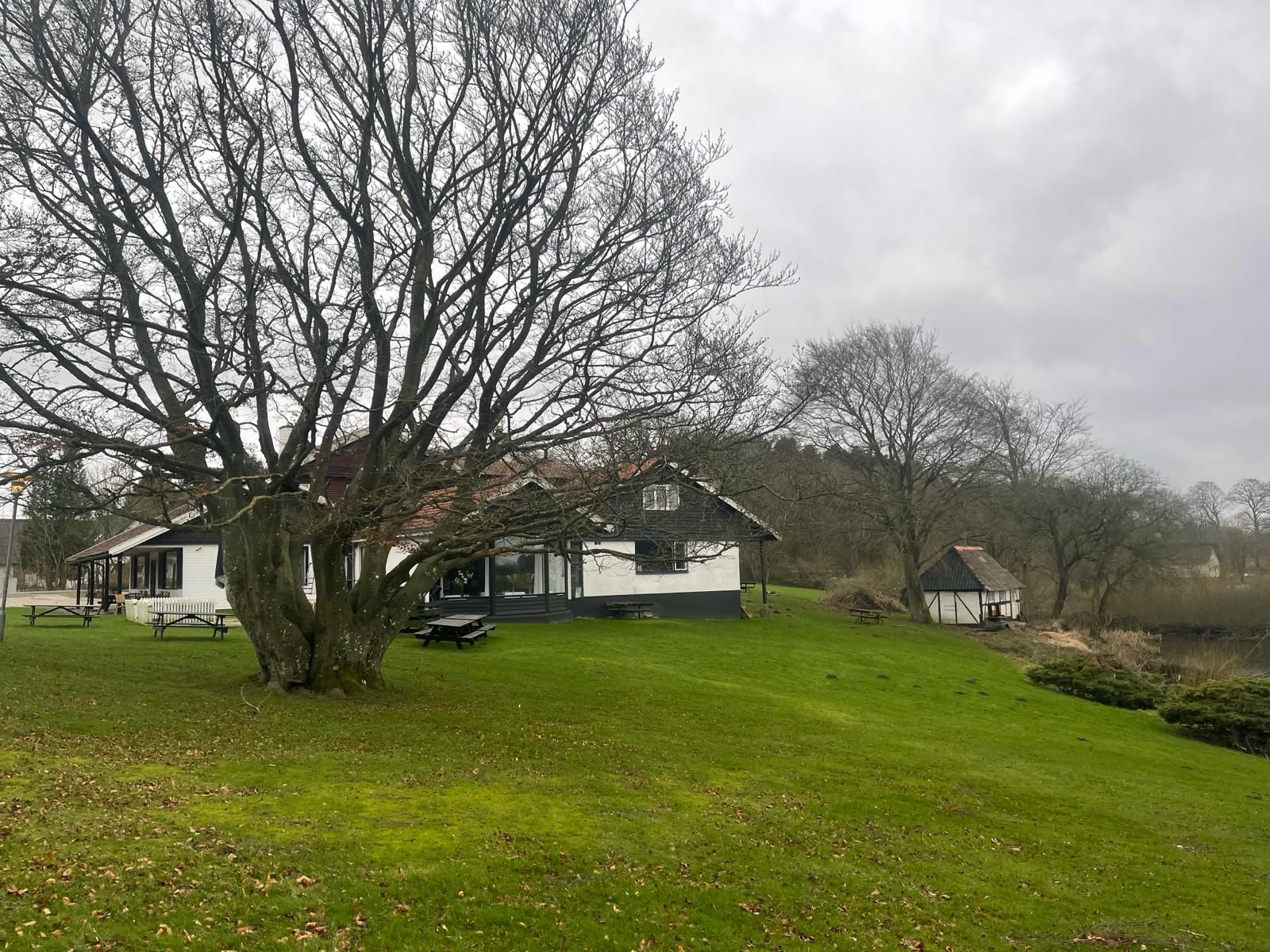 Mørkenborg Kro, en hyggelig kro med smukke haver, parkerede biler og en idylisk have med græs og træer