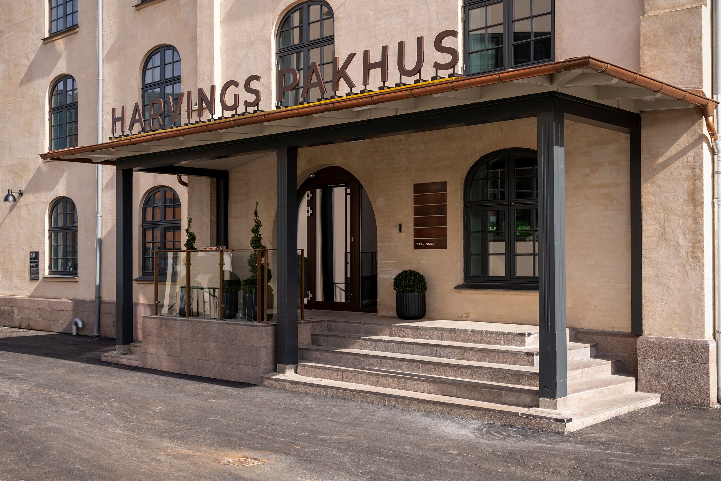 Harvings Pakhus har en flot facade med store vinduer og en slank søjle. Der er en indgang med smukke trapper og en udsmykket