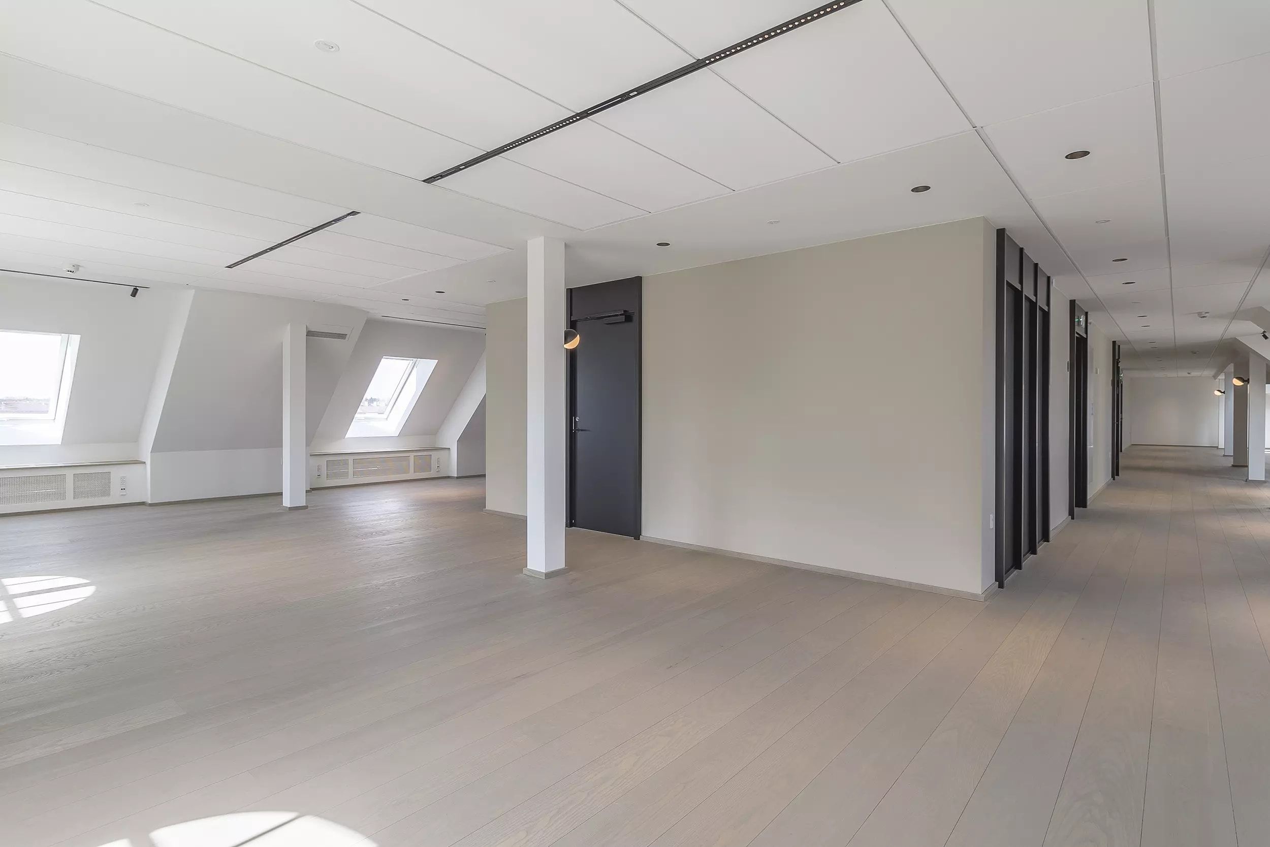 Langs en kølig og ren gang er der lyse lofter, hvide vægge og gulve samt to vinduer i loftet og to døre