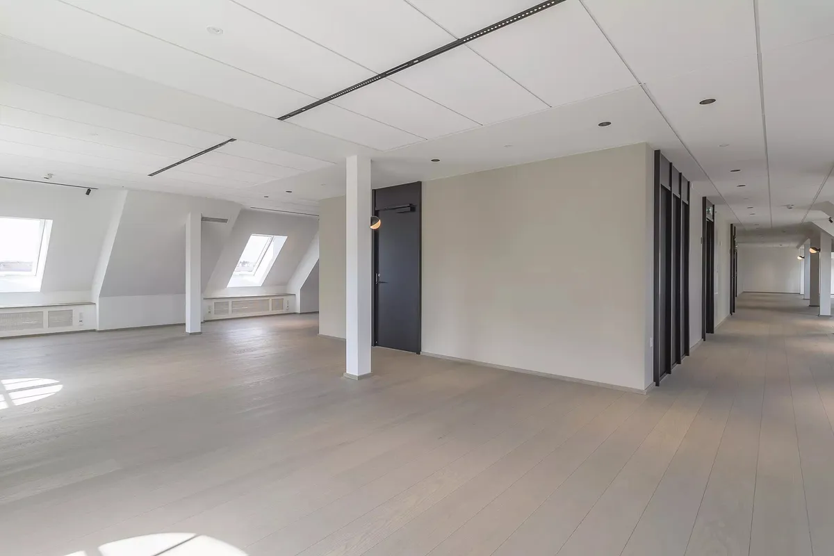 Langs en kølig og ren gang er der lyse lofter, hvide vægge og gulve samt to vinduer i loftet og to døre