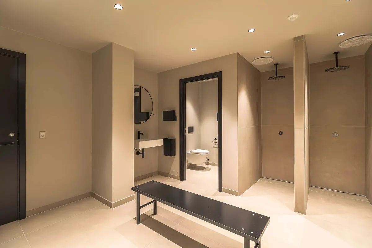 En moderne og minimalistisk toiletrum med en hvid toilet, et badekar, et spejl og en lysekron