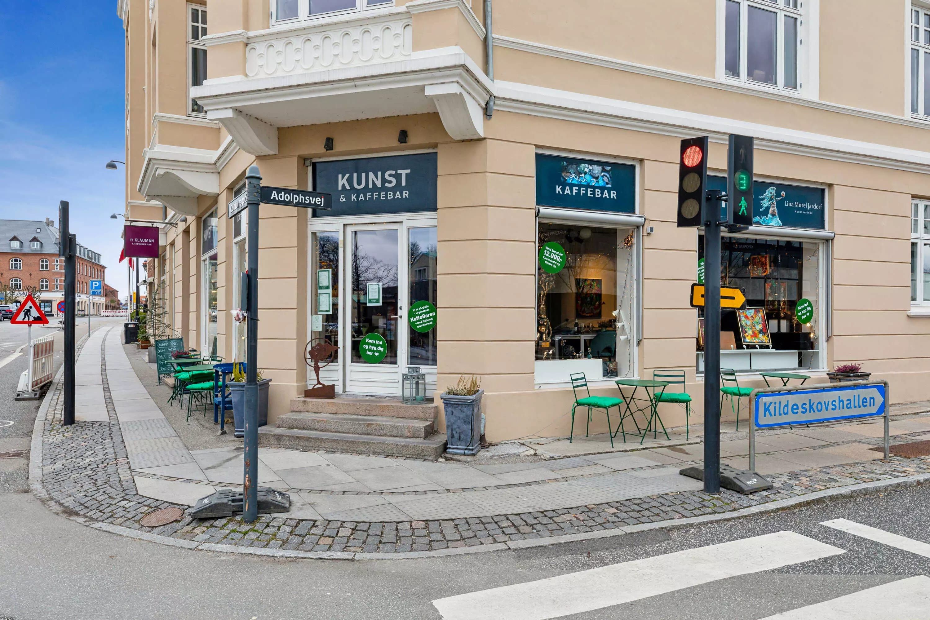 Kunst og Kaffebar er en café på Adolphsvej, med terrasse og grønne stole. Bygningen har kunstgalleri, og der er en