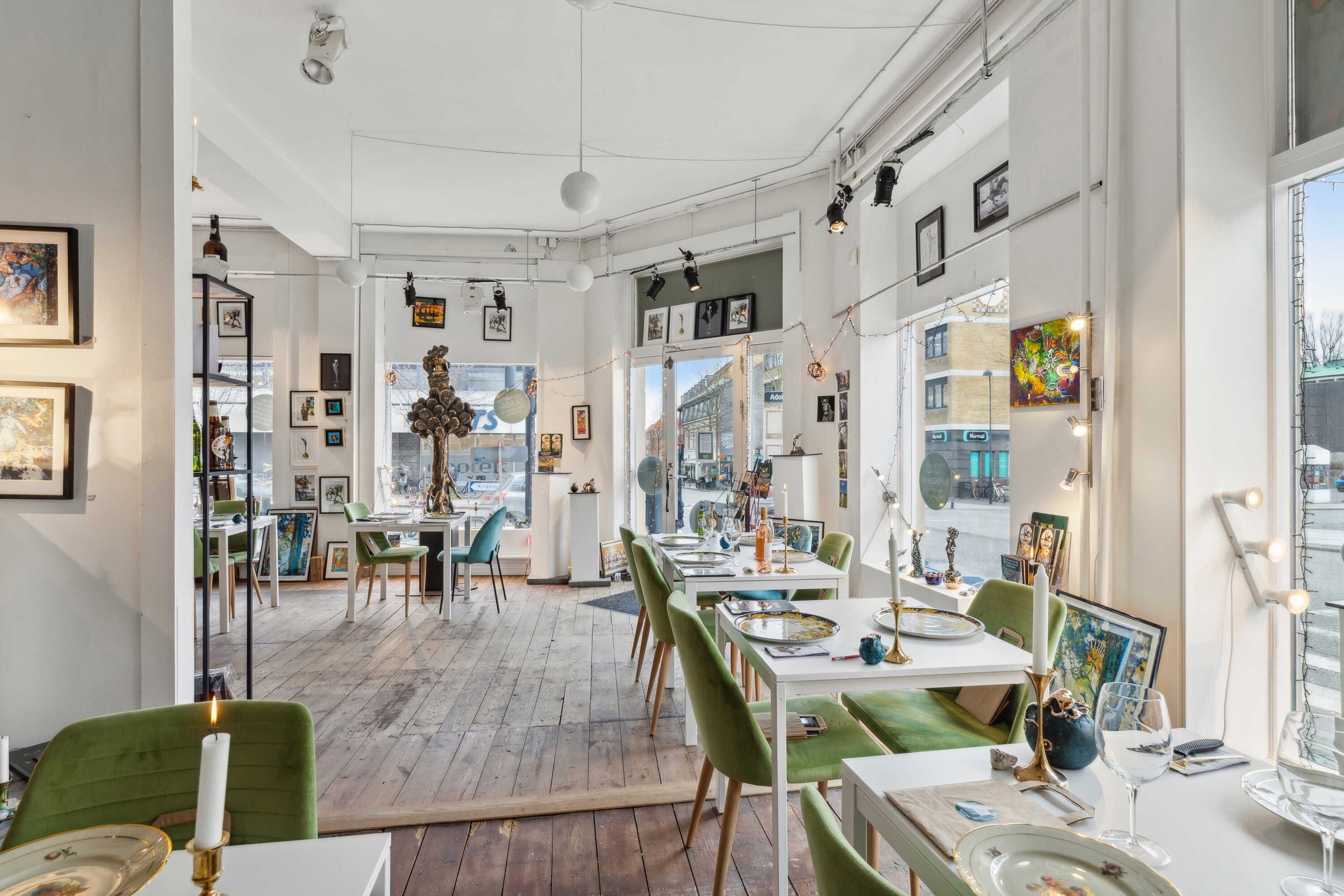 Lys indrettet café med møbler og vægdekorationer i retrostil og et glas på bordet med en lille lysestage