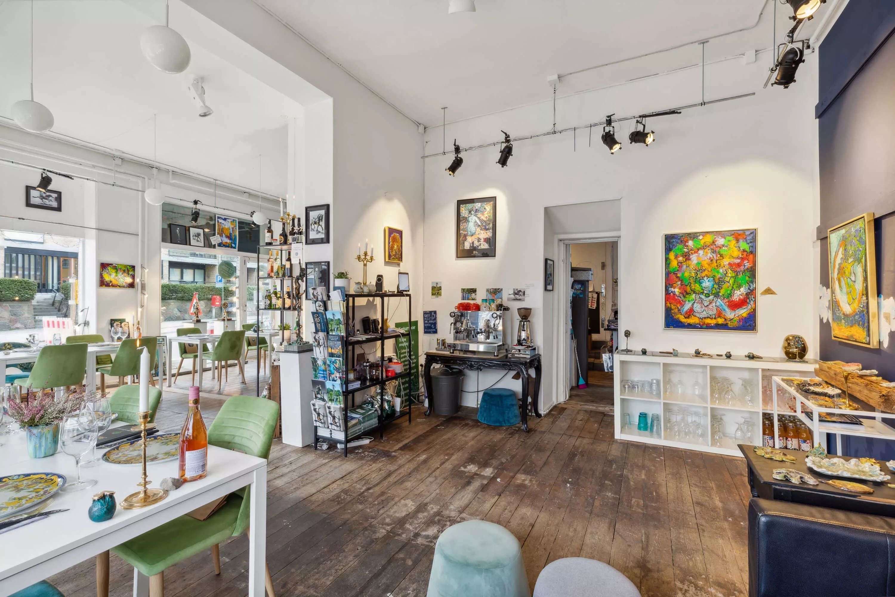 Indretning af café med stole, borde, malerier, udstillingsskabe og glas på hylder og borde