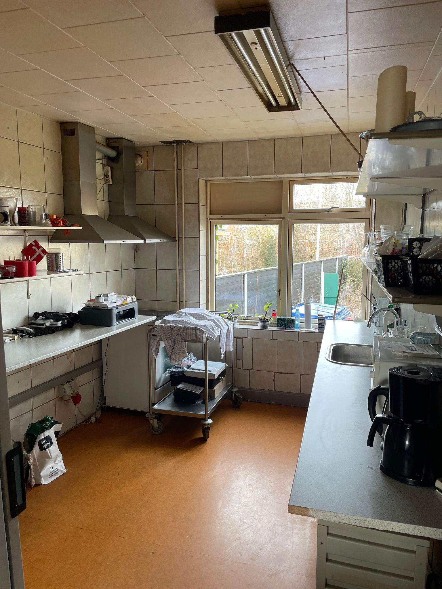 En køkken med apparater og ting i hjørner og udstyr, såsom en ovn, et kaffemaskine, og en vaskemaskine i et område med et